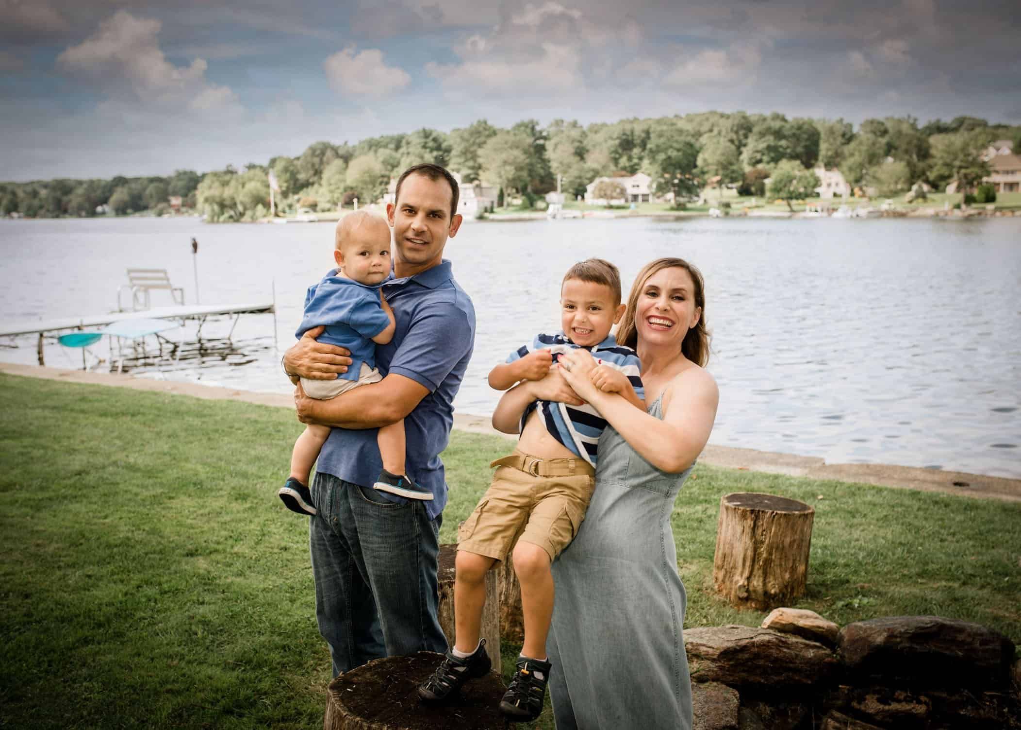 Family of 4 down by the lake, parents holding both boys