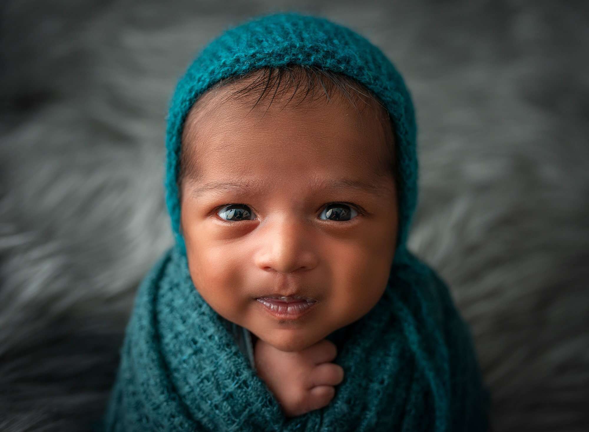 newborn Indian boy wide awake swaddled in teal