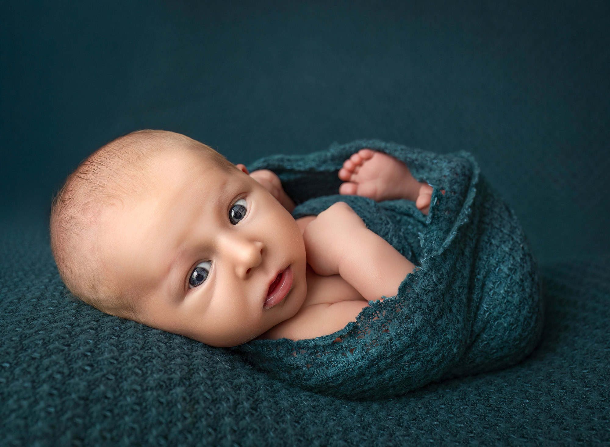 keep baby calm during the photoshoot Levi awake and bundled in teal knit, tiny toes peeking out on matching fabric.