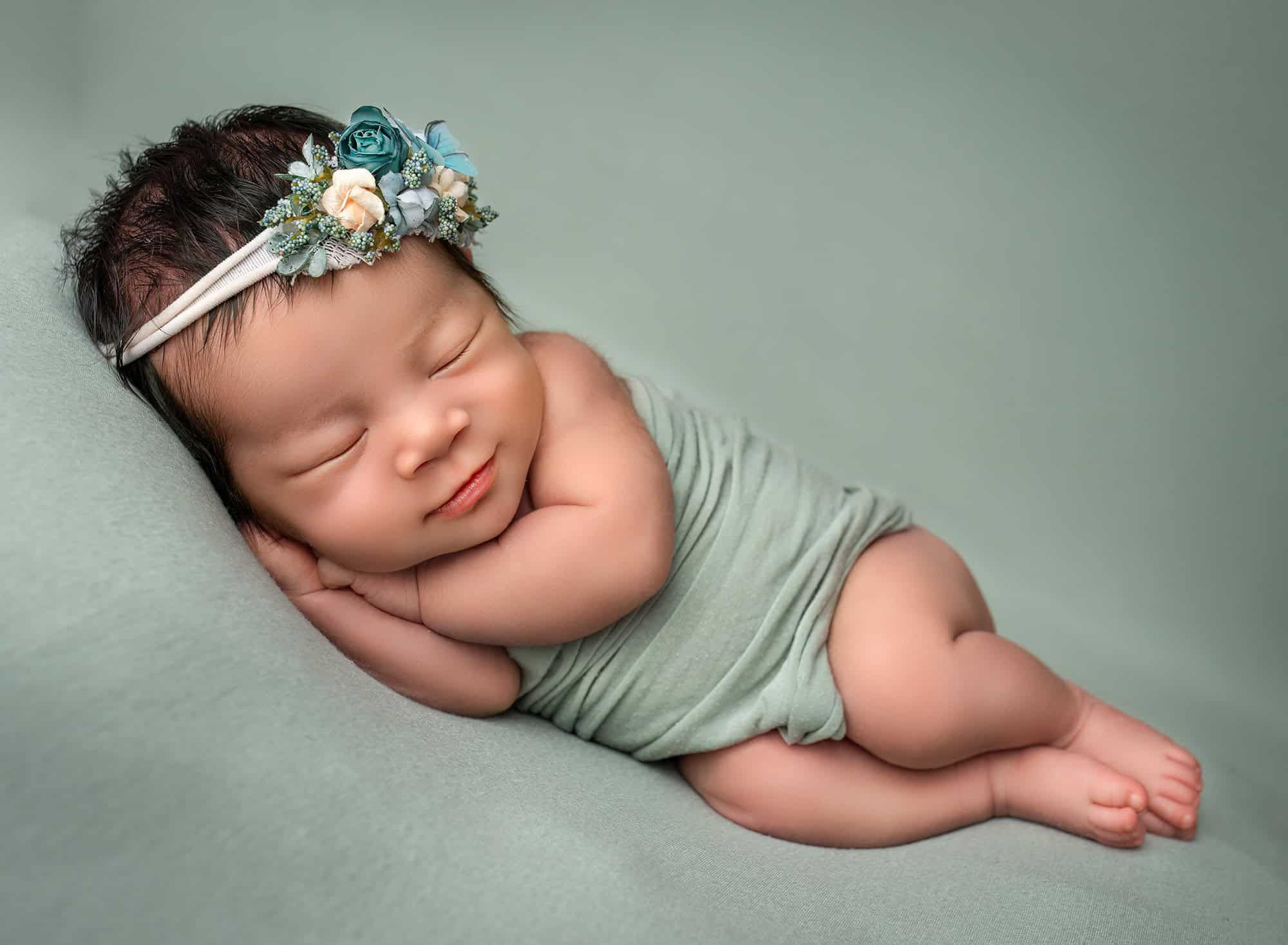 newborn photographer CT newborn baby sleeping on her side on a green background
