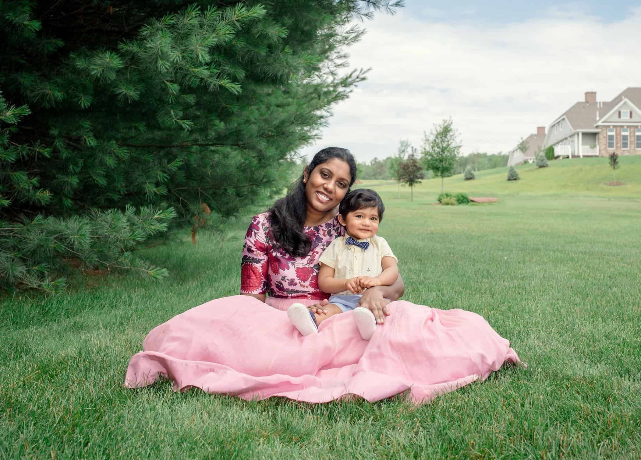 Mom and 8 mo old boy sitting on grass smiling at camera