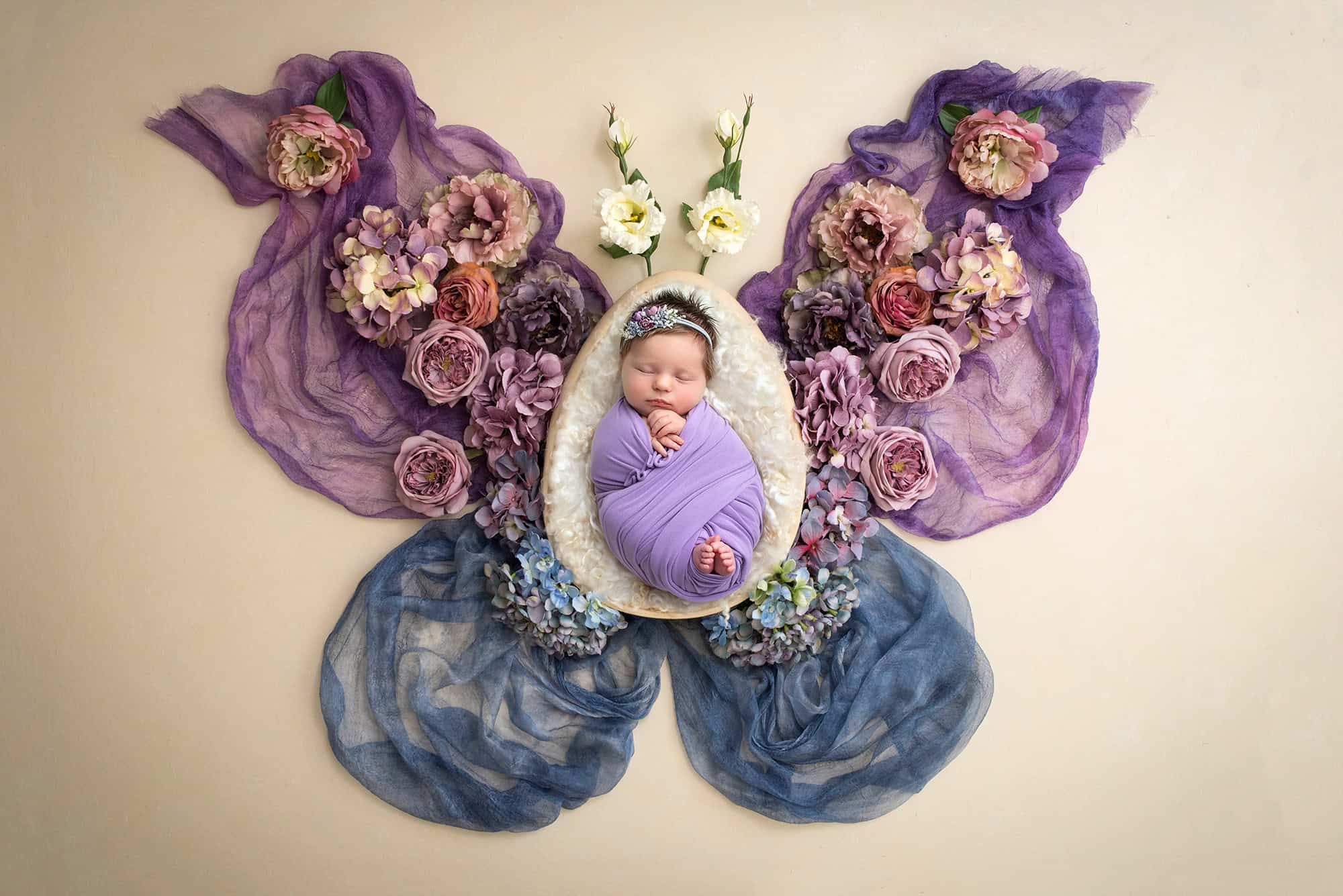 Newborn Photos with Butterflies sweet newborn baby girl asleep swaddled in purple inside of a butterfly