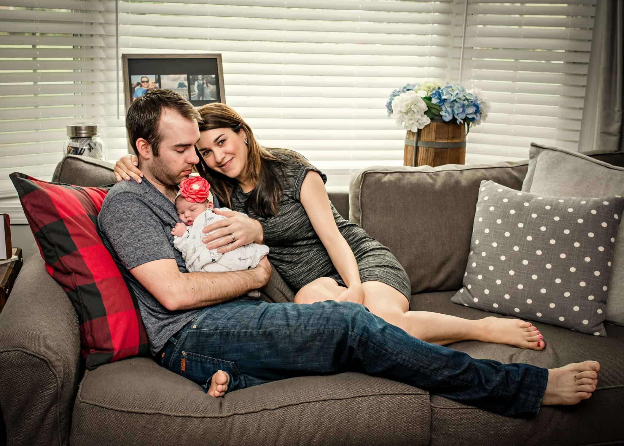 Mom and Dad holding sleeping newborn on their couch
