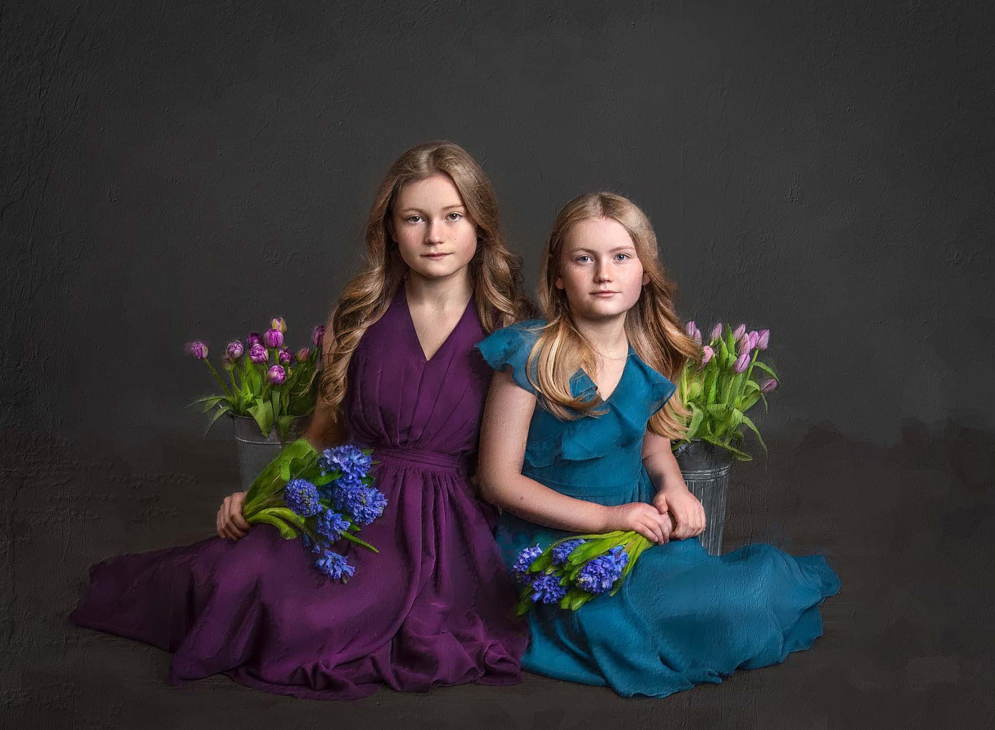 hand-painted canvas portrait of two young girls holding blue and purple flowers