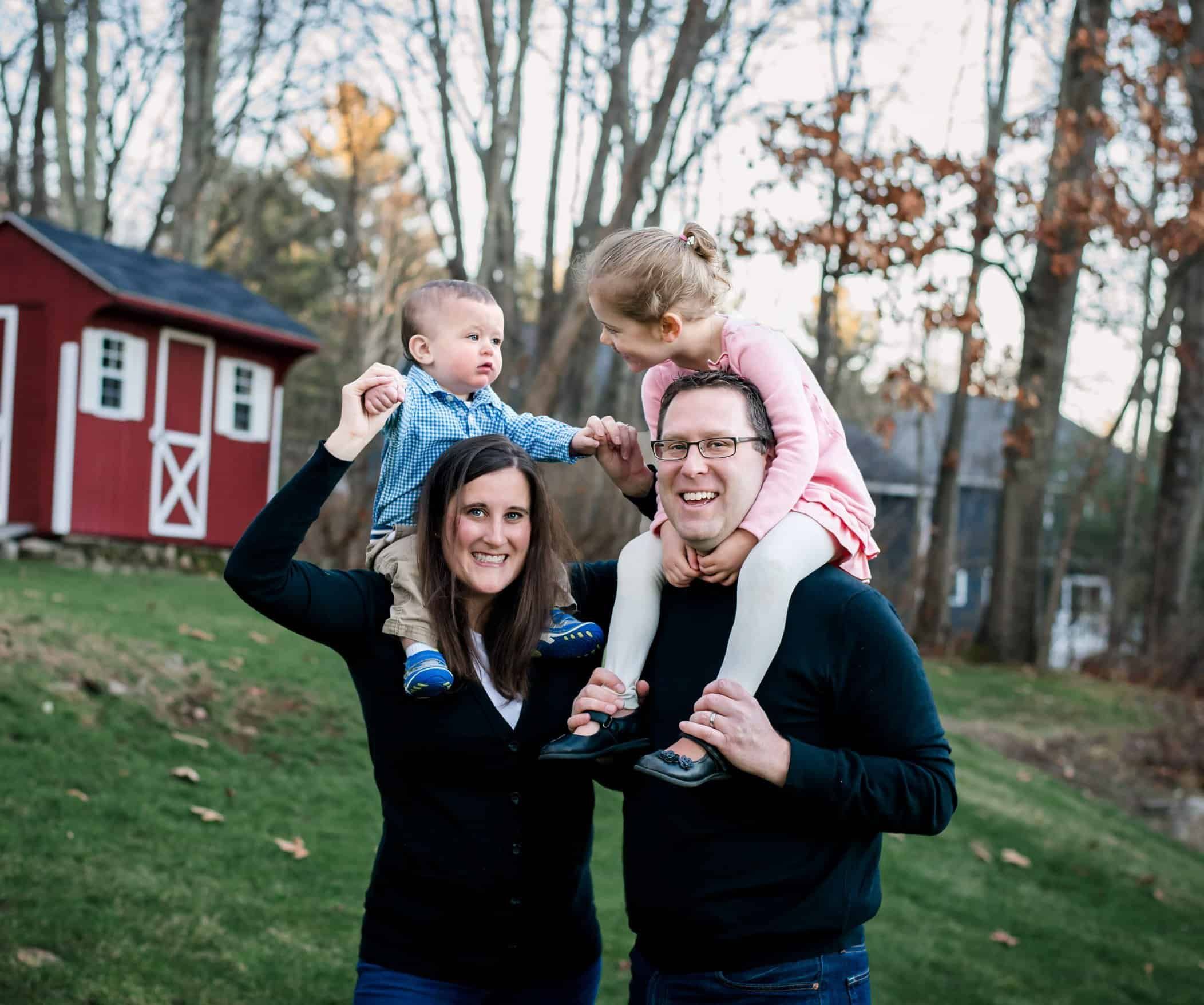 Mom and Dad giving their two little kids shoulder rides across the backyard