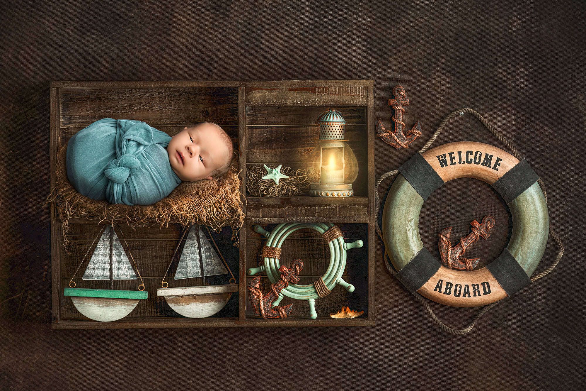 newborn photography in CT newborn baby wrapped and sleeping in a welcome aboard crate