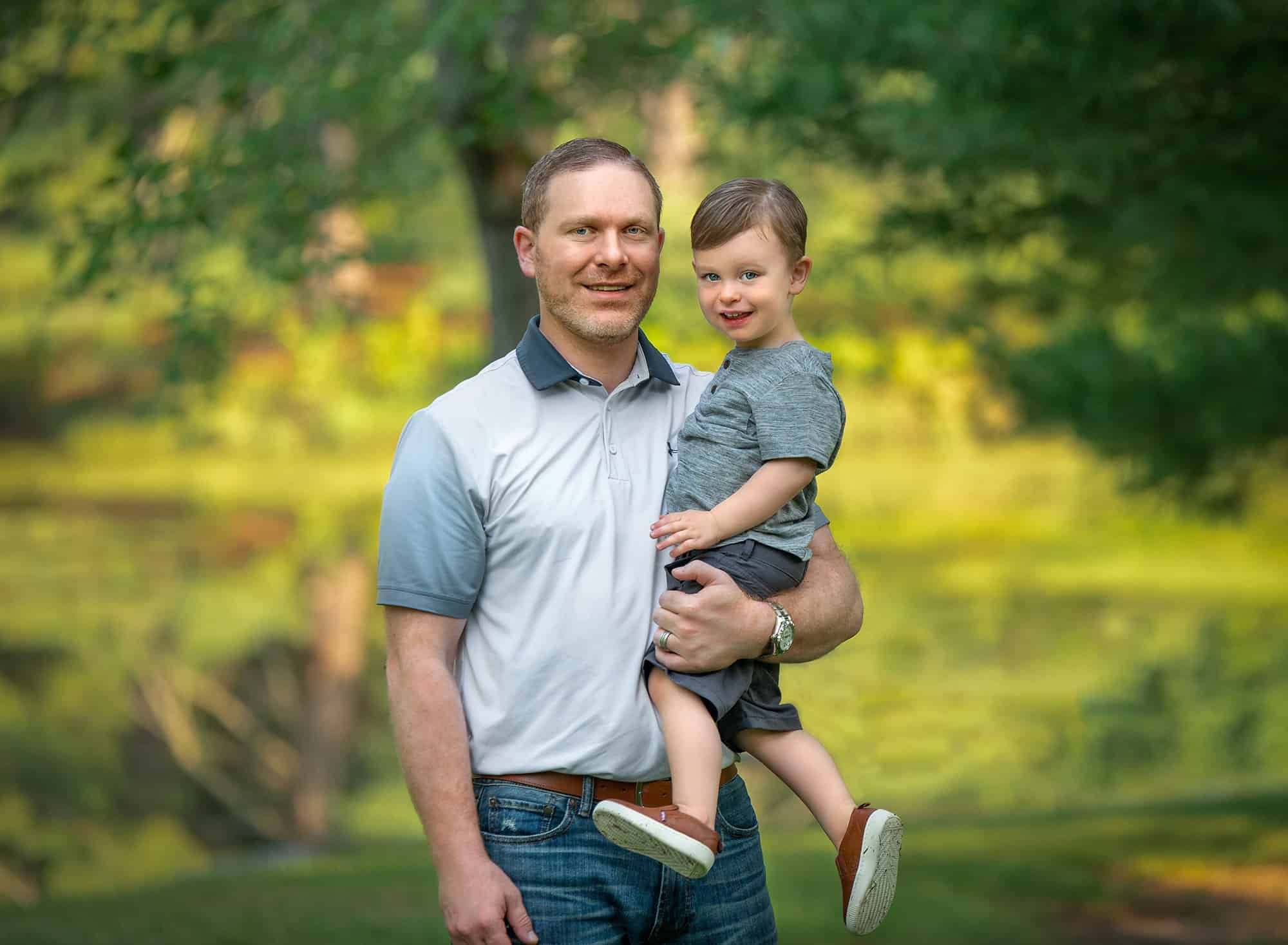 father holding two year old son in nature
