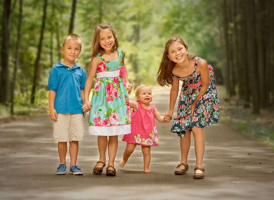 four young siblings taking a walk in the woods