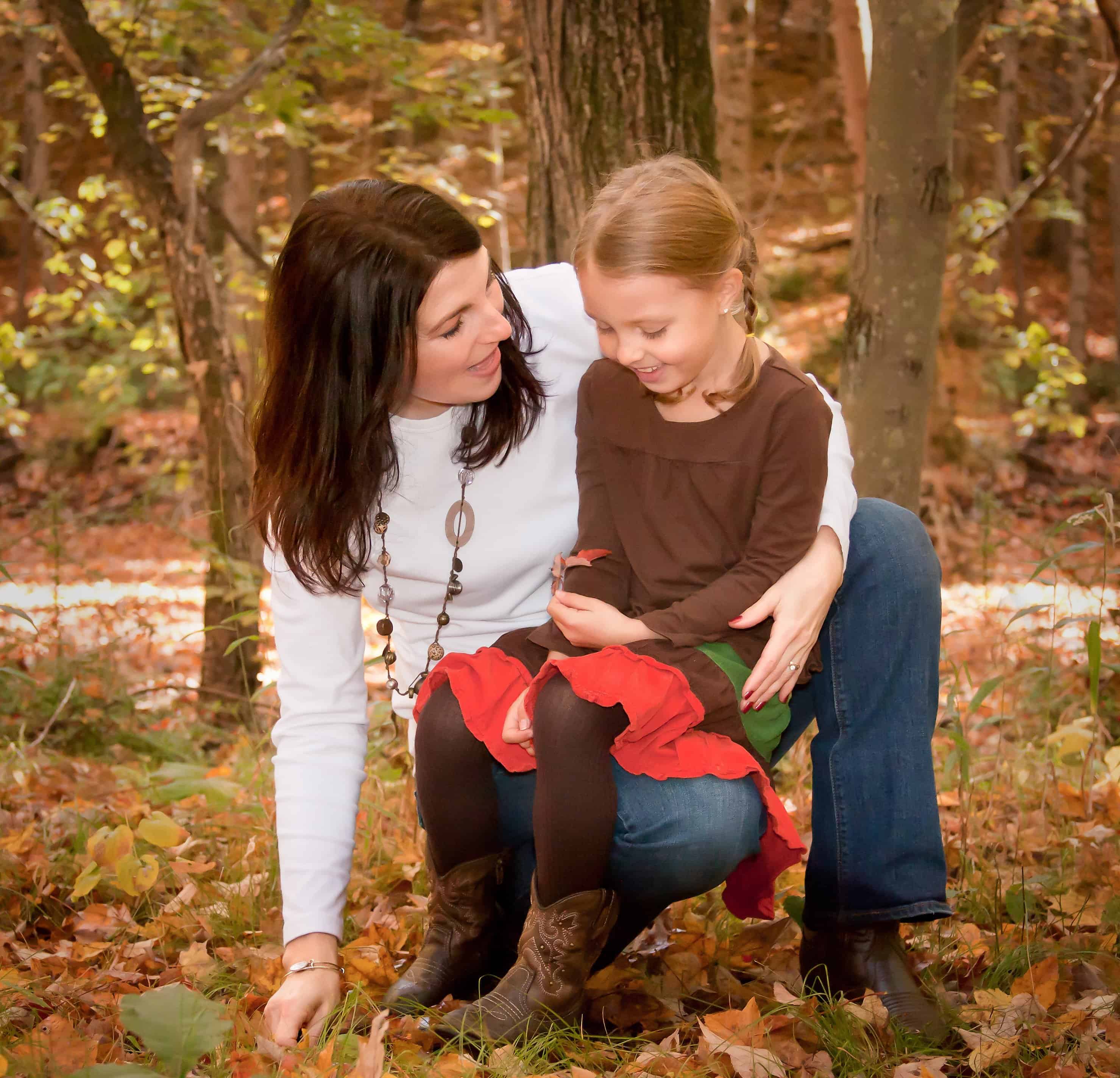 Mom and young daughter having a talk in the fall woods