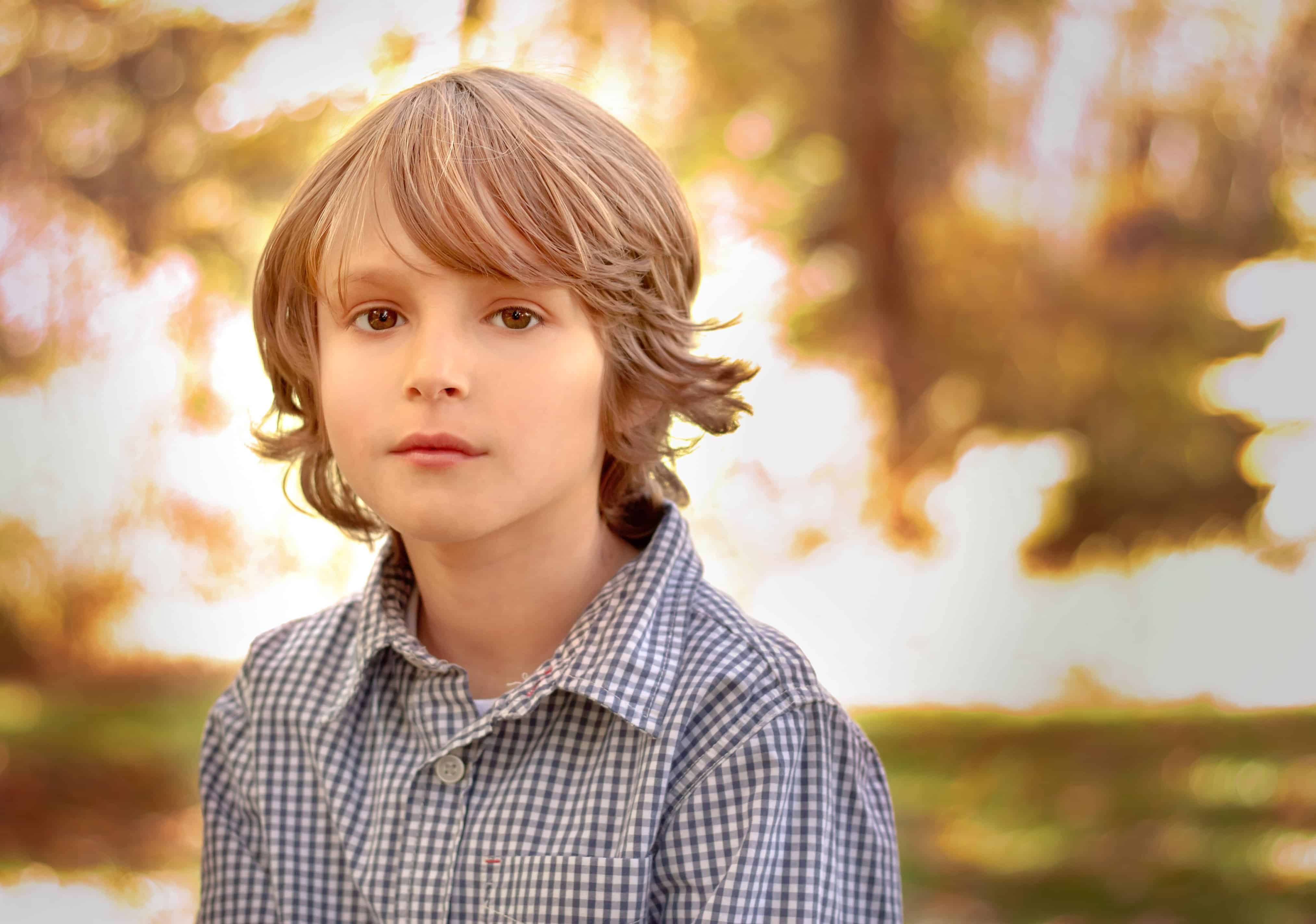 young boy looking serious with bright fall colors behind him