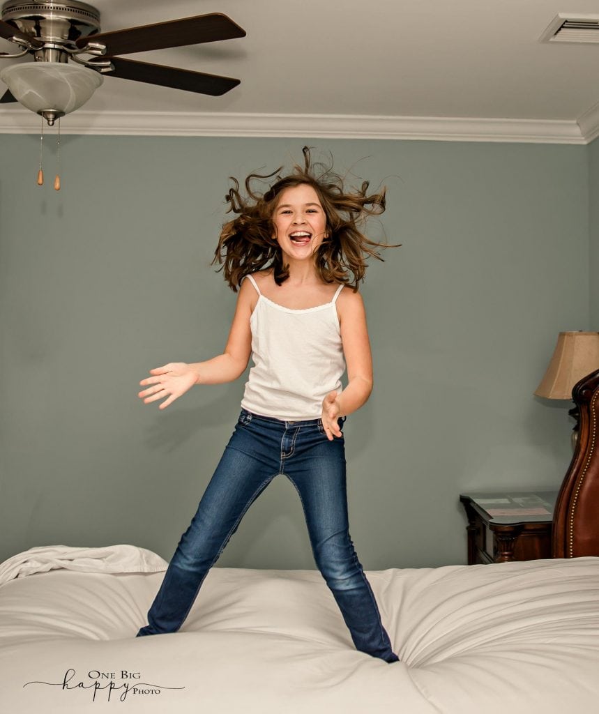 little girl jumping on her parents bed, hair flying