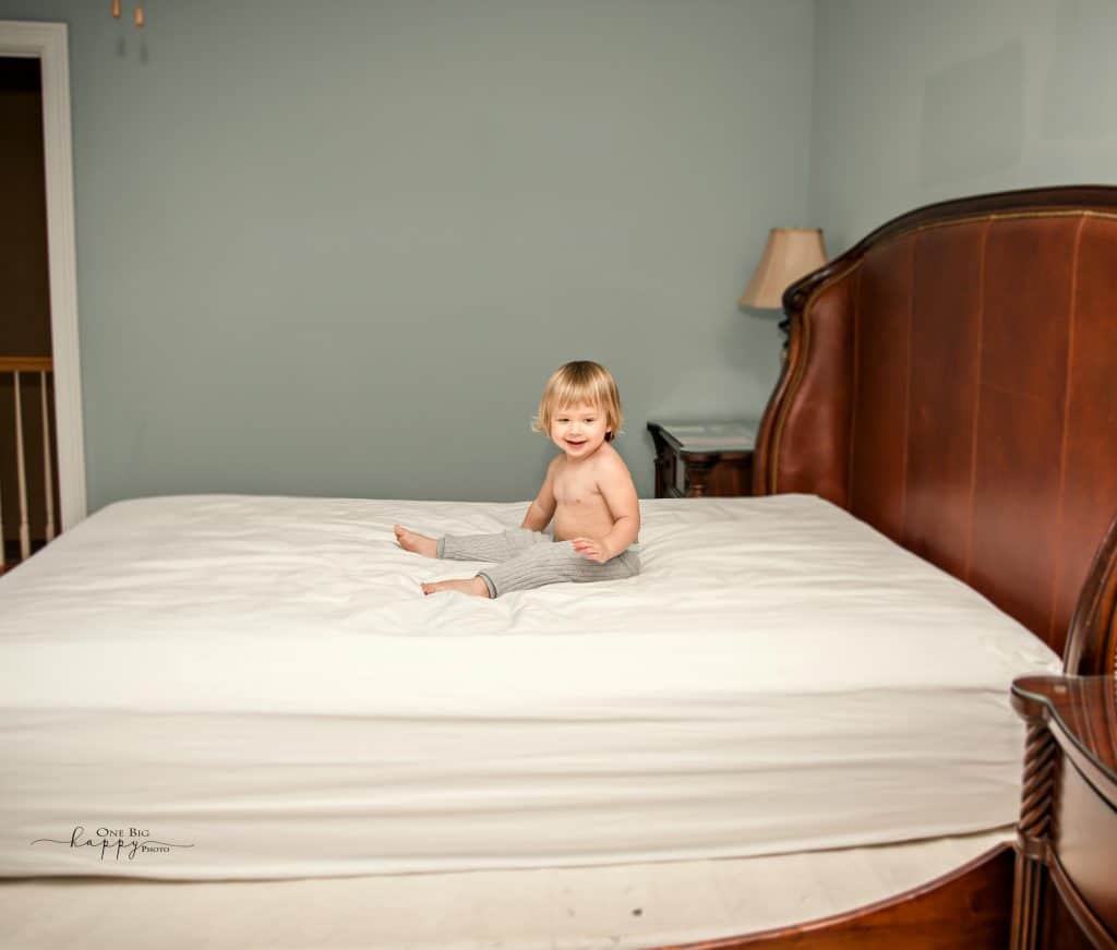 Toddler sitting on parents bed smiling