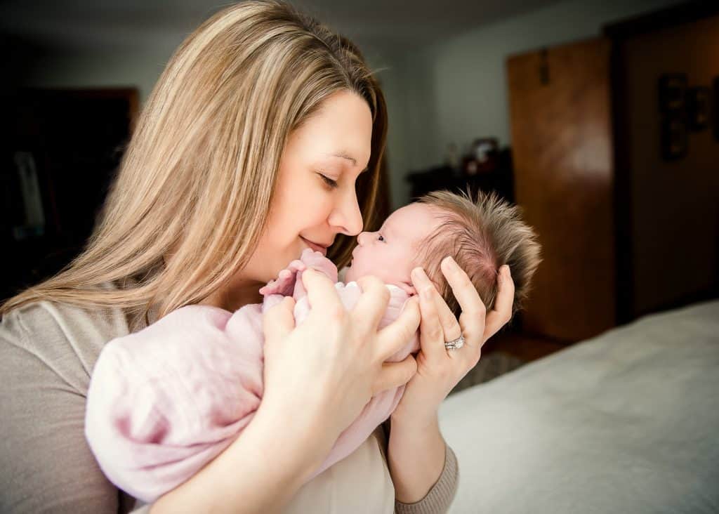mom holding newborn girl nose to nose