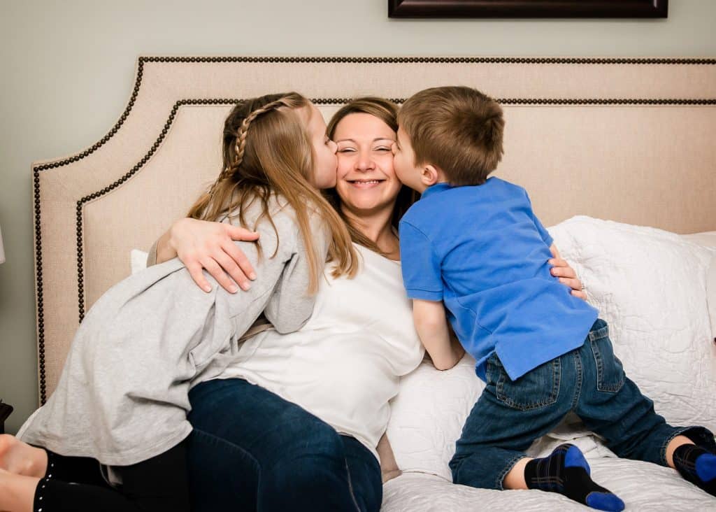 girl and boy give Mom kisses on cheeks