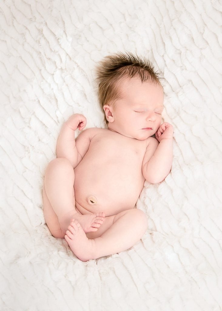 newborn baby girl laying on white blanket asleep