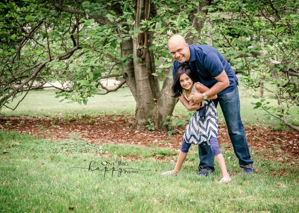 Daddy and daughter bear hug outside in summer garden