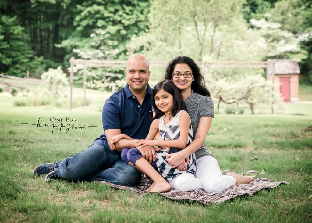 Family of 3 seated in summer garden for portrait