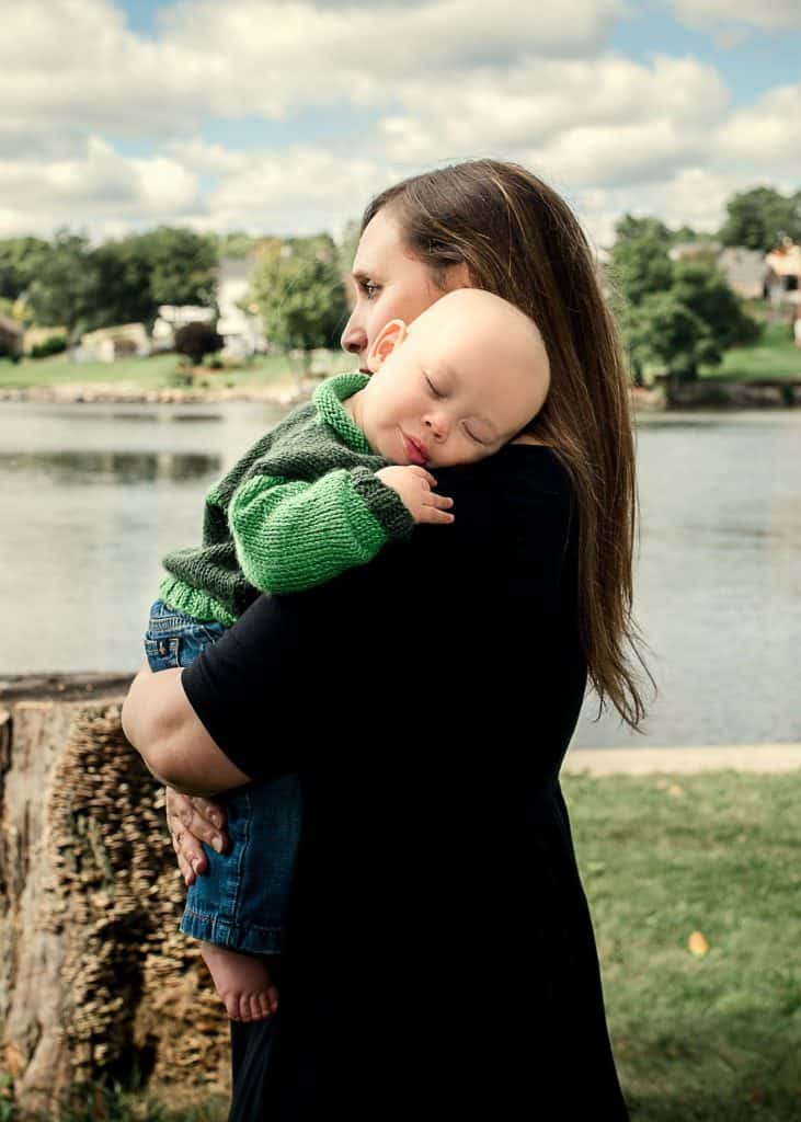 Mom holding her sleeping 6 month old son outside in front of the lake One Big Happy Photo