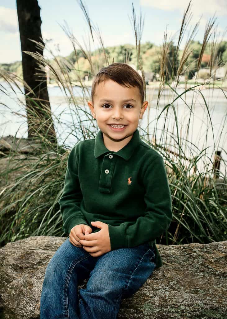 3 year old boy posing on a rock in front of a lake and some sea grass One Big Happy Photo