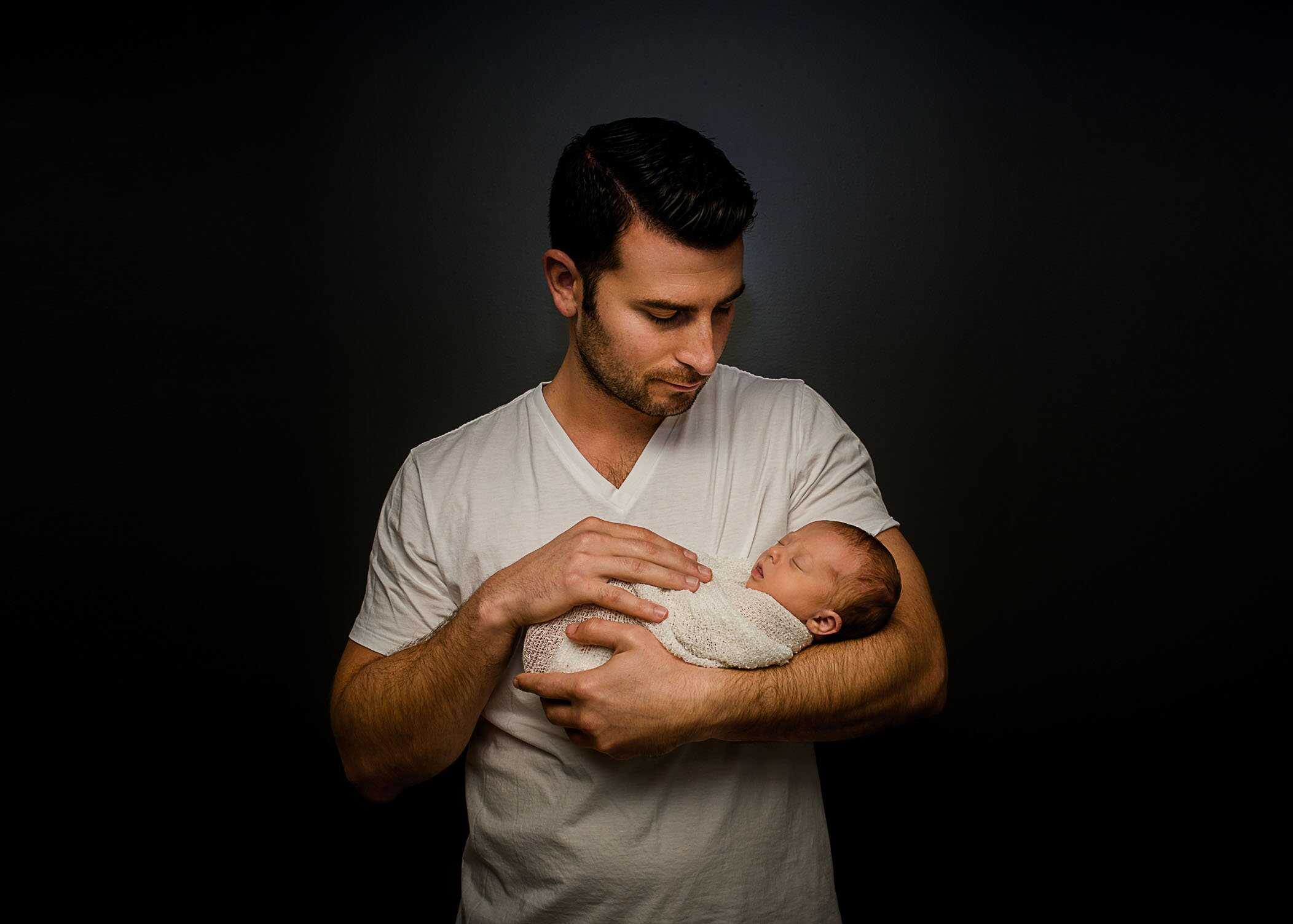 Dad holding his newborn daughter in his arms