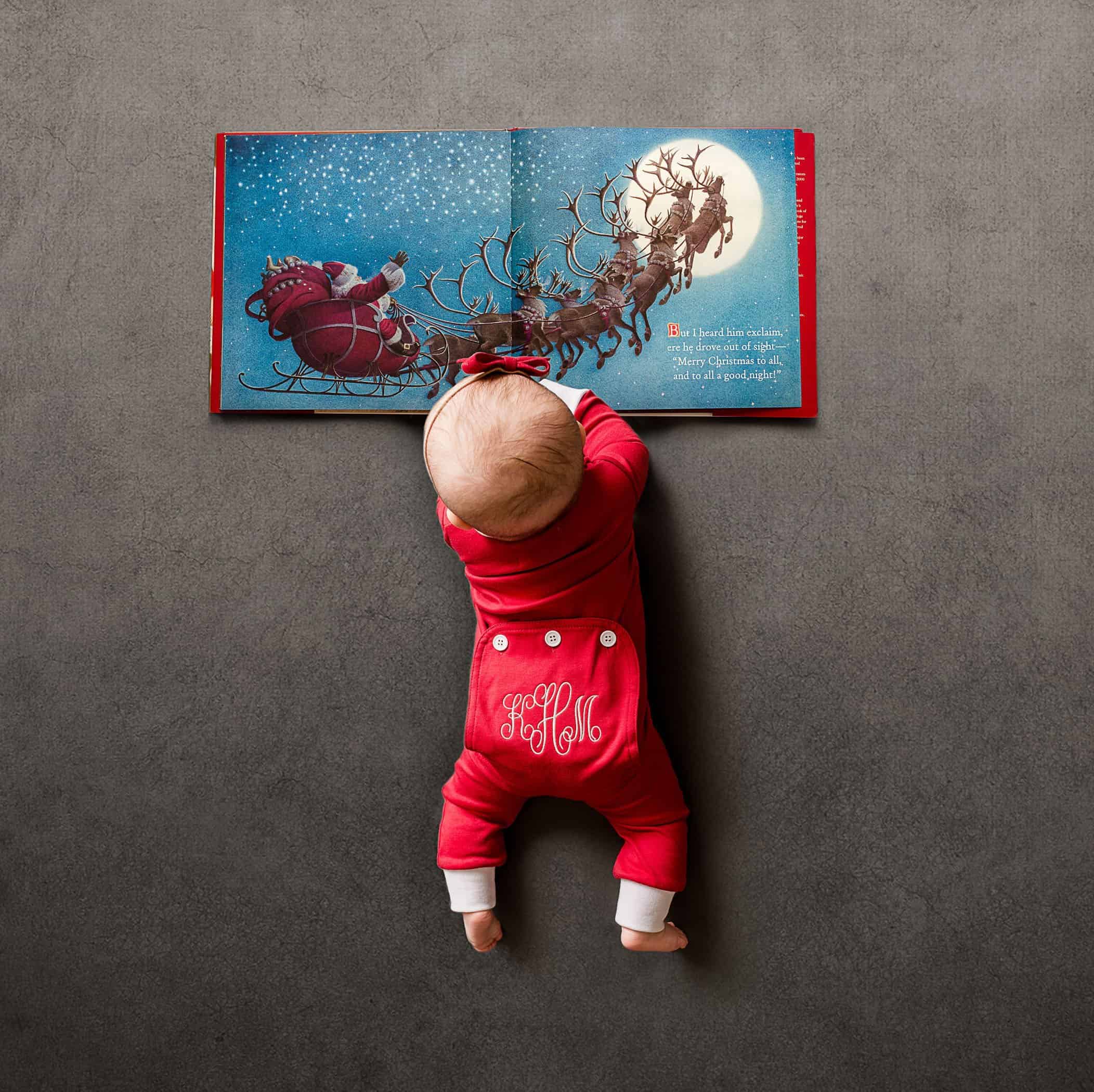 6 mo old baby girl lying on floor looking at Santa book One Big Happy Photo