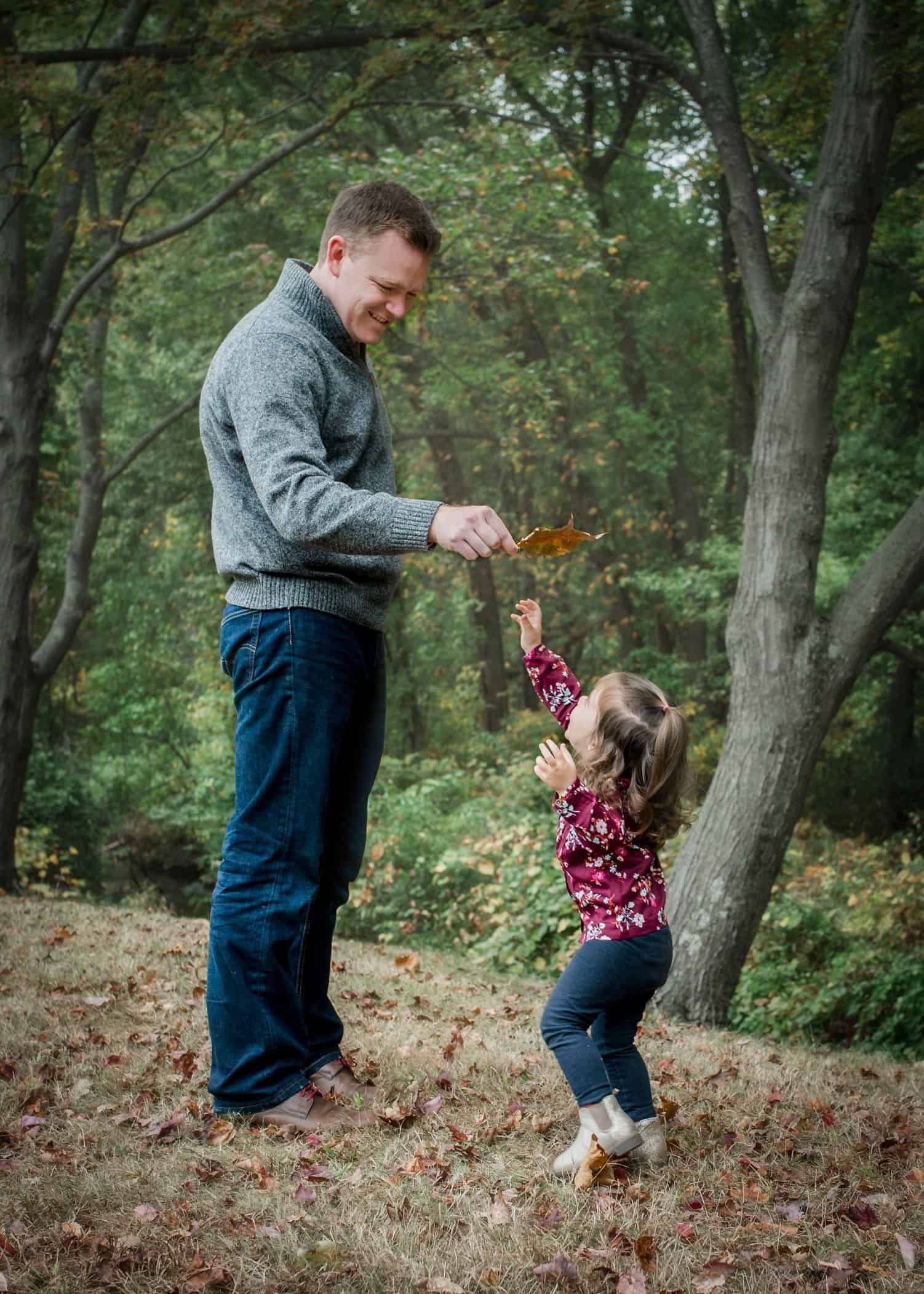 Dad holding big leaf for 2 year old to jump and get