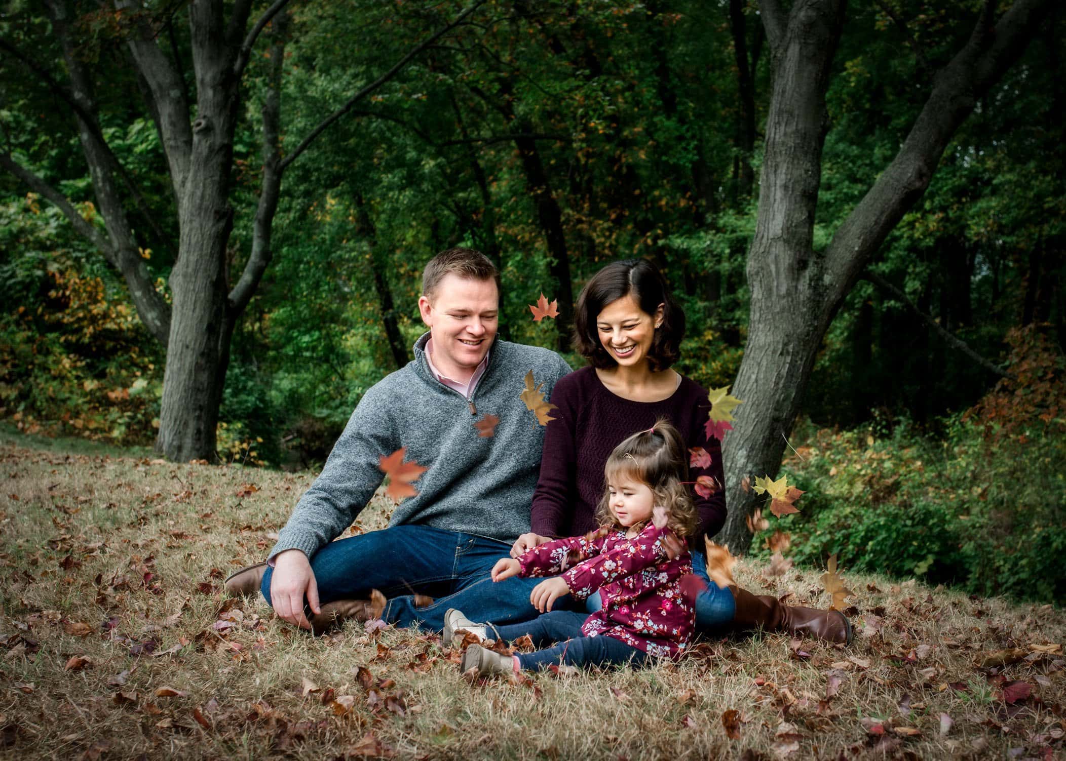 2 year old and mom and dad playing with fall leaves