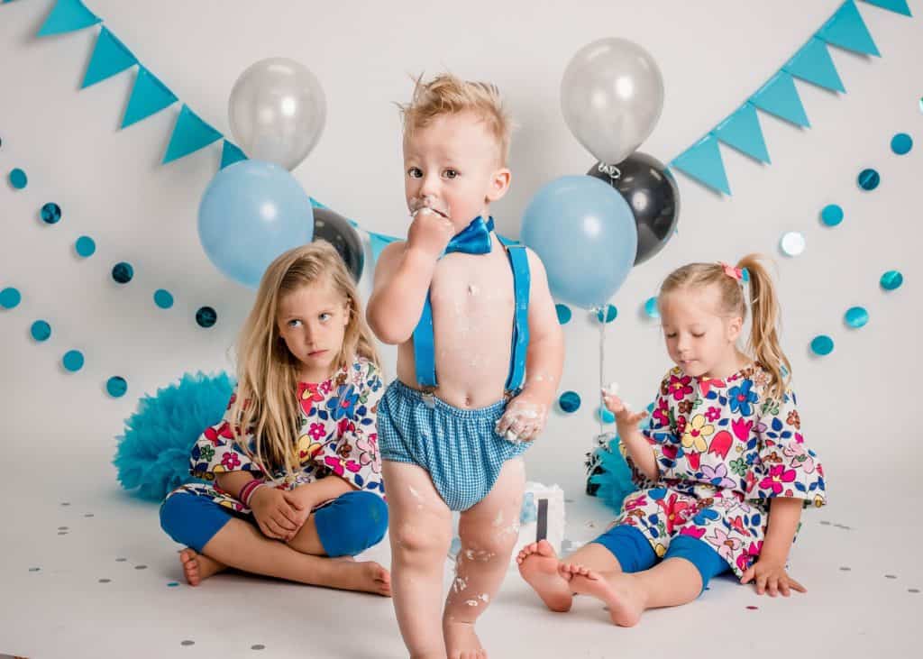 12 month old boy and his sisters at his cake smash session