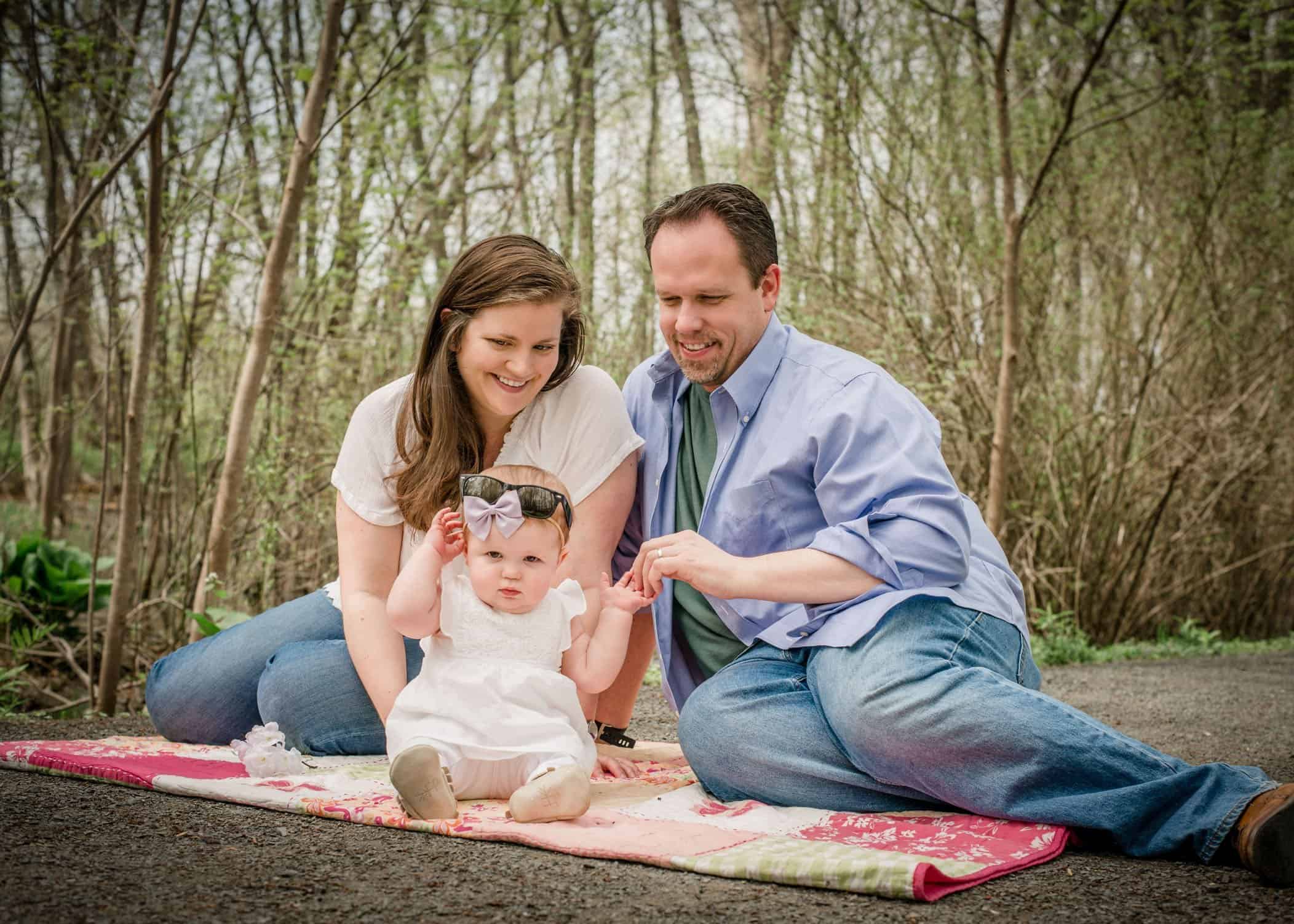 9 mo old baby girl sitting outside with parents on blanket