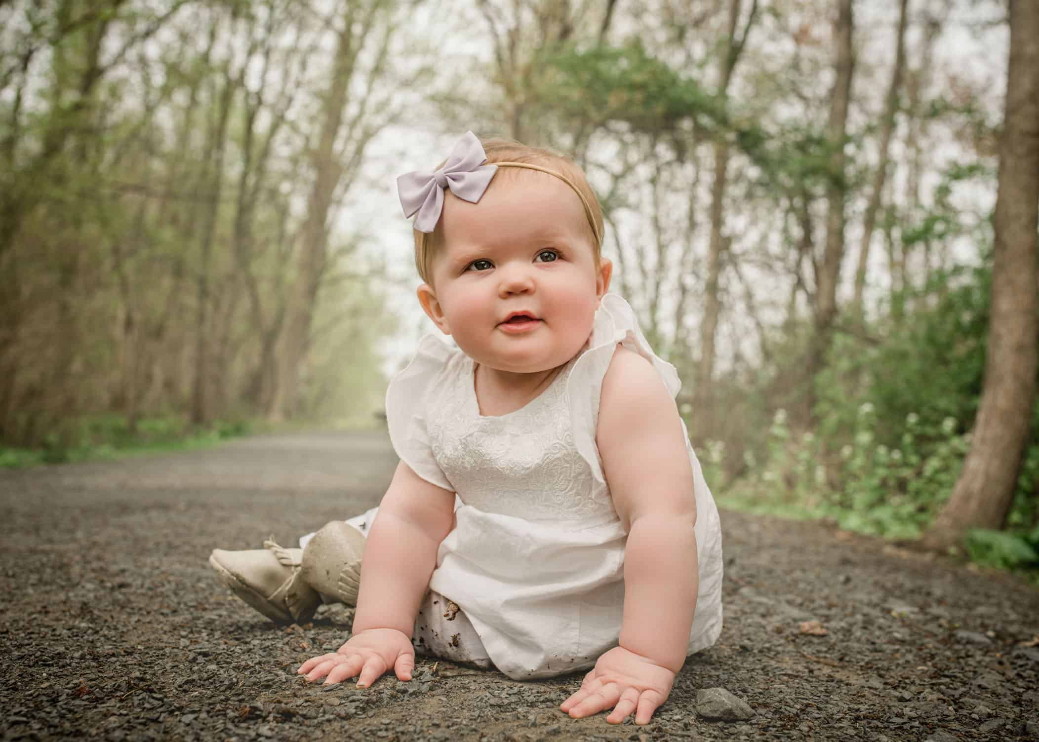 9 mo old baby girl sitting on path in garden