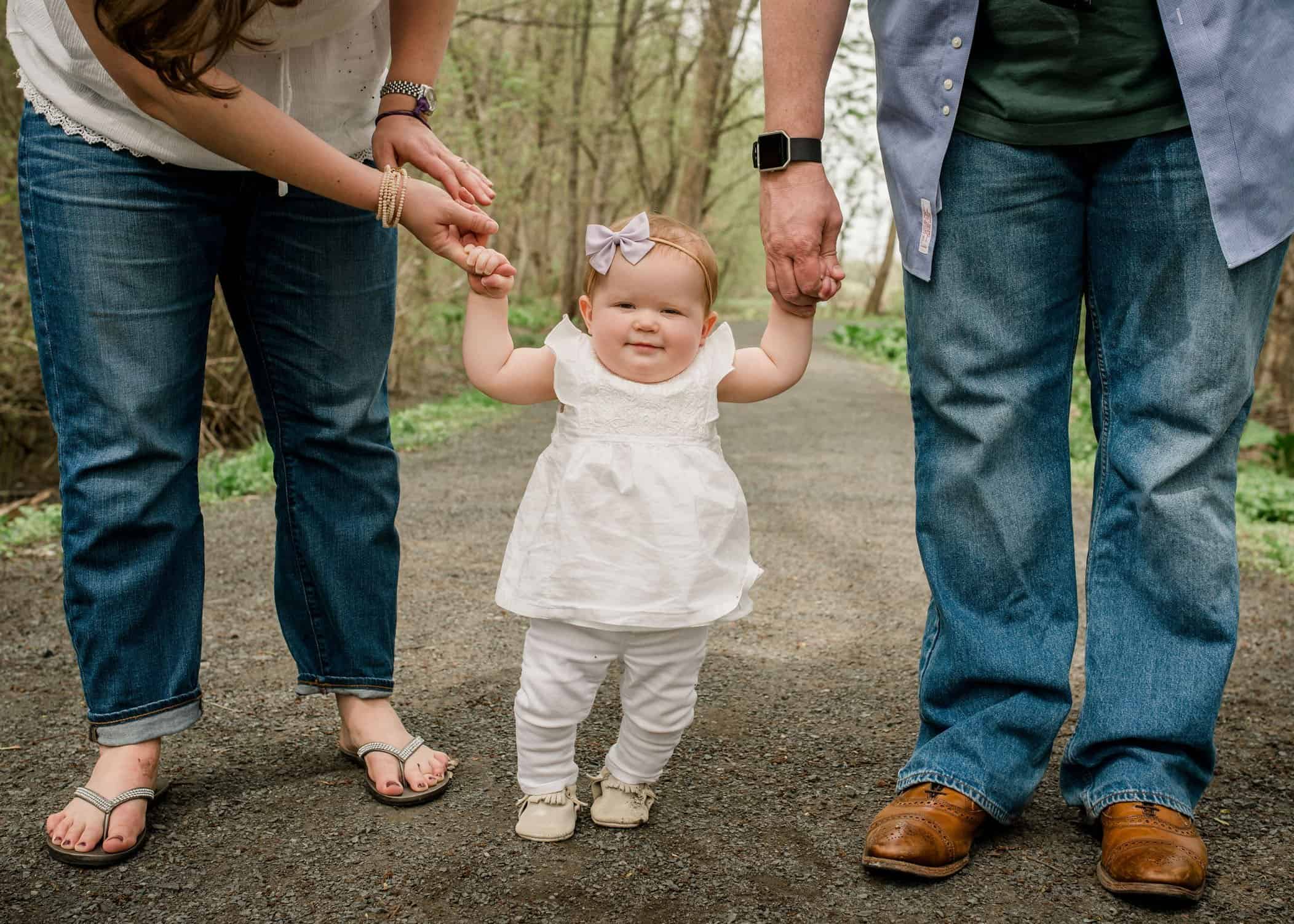 9 mo old baby girl standing holding parents hands