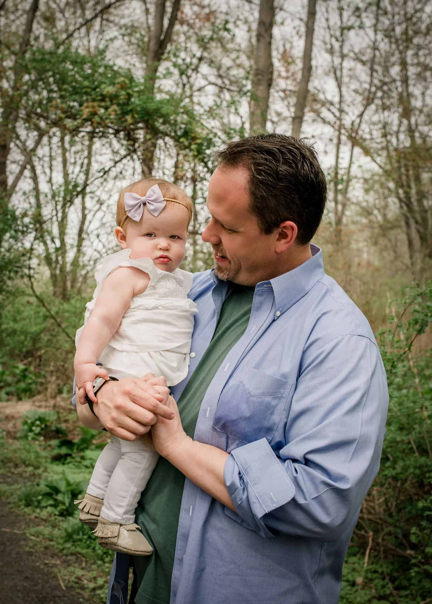 Dad holding 9 mo old baby girl in garden