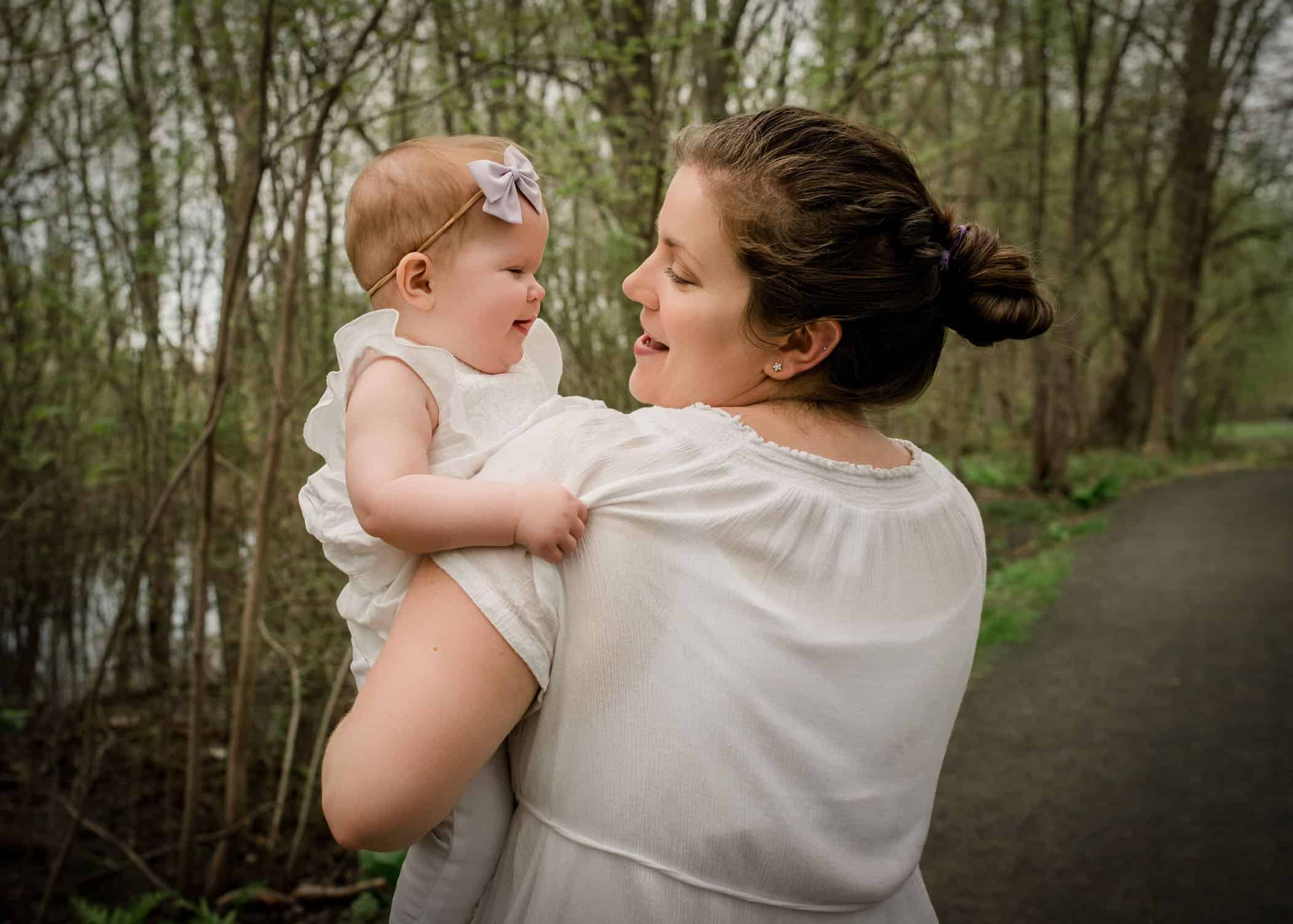 Mom holding 9 mo old baby girl in garden