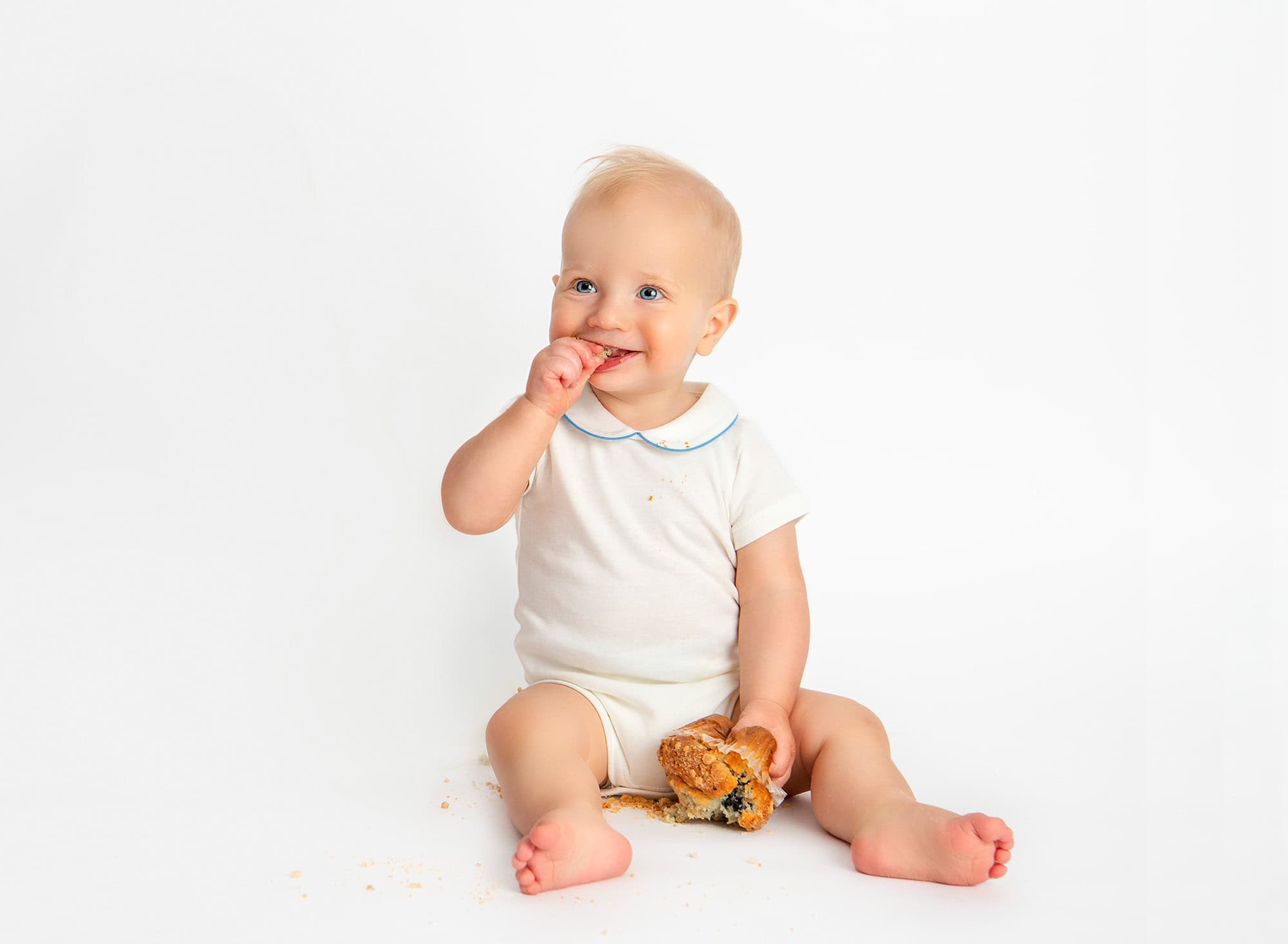 All White Smash Photoshoot Julian smashing a blueberry muffin during his first birthday photoshoot.
