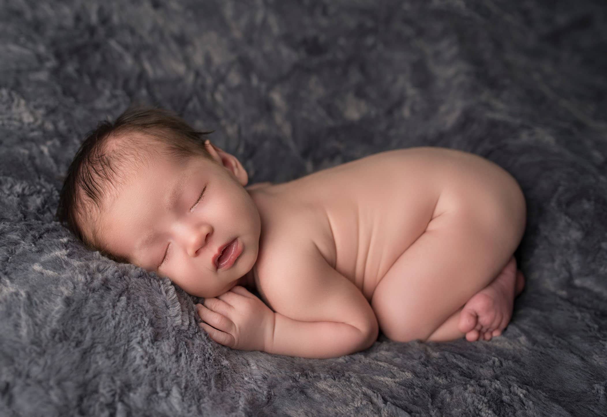 newborn baby boy in bum up pose on grey fur