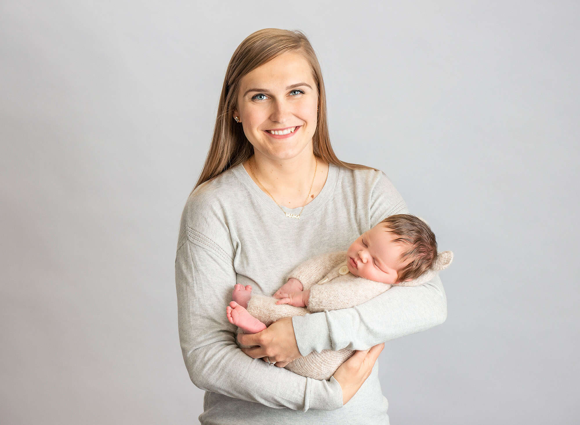 mom holding asleep newborn baby boy dressed in sweater romper