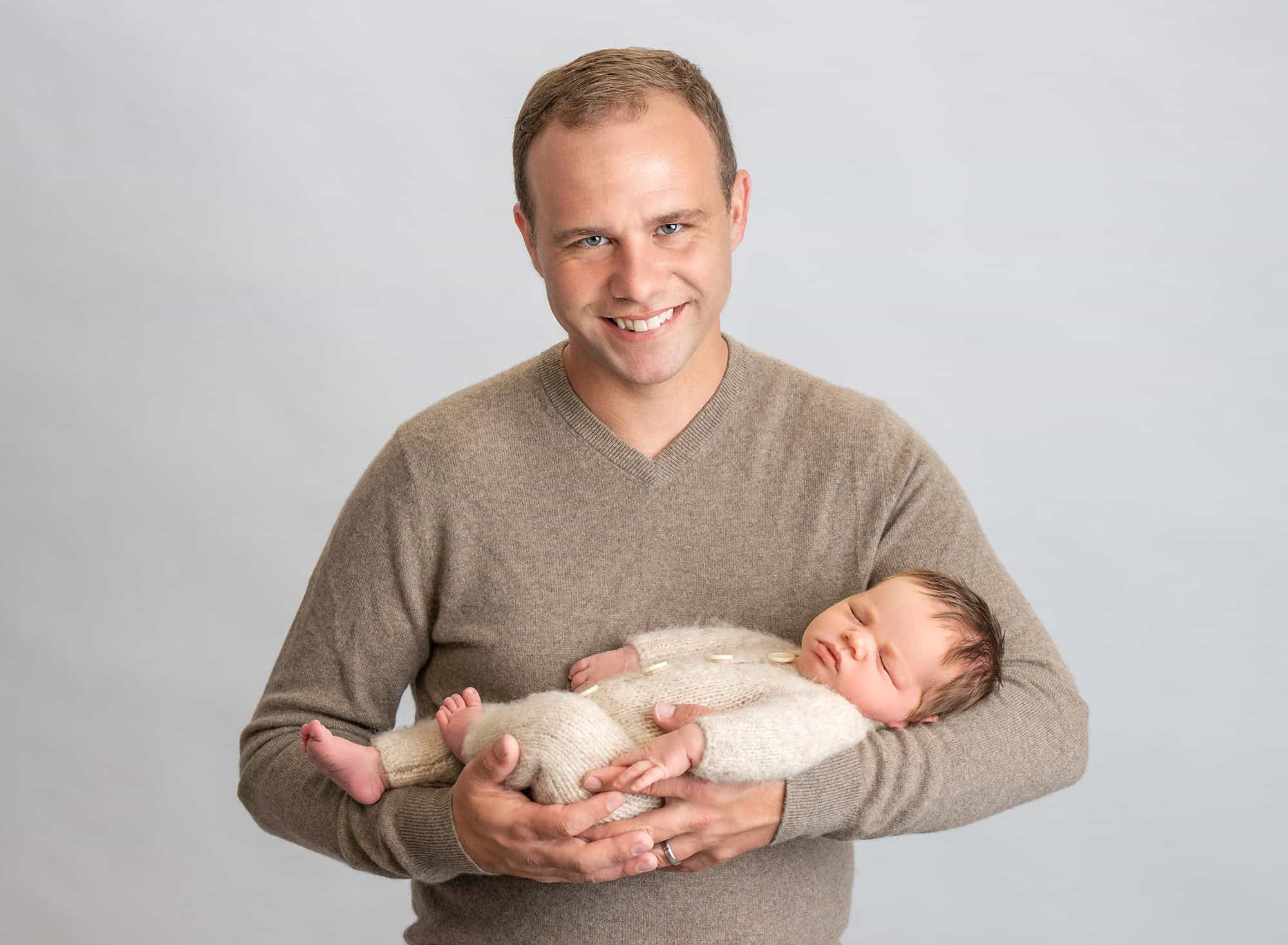 Connecticut Newborn Photography dad cradling asleep newborn baby boy in sweater romper