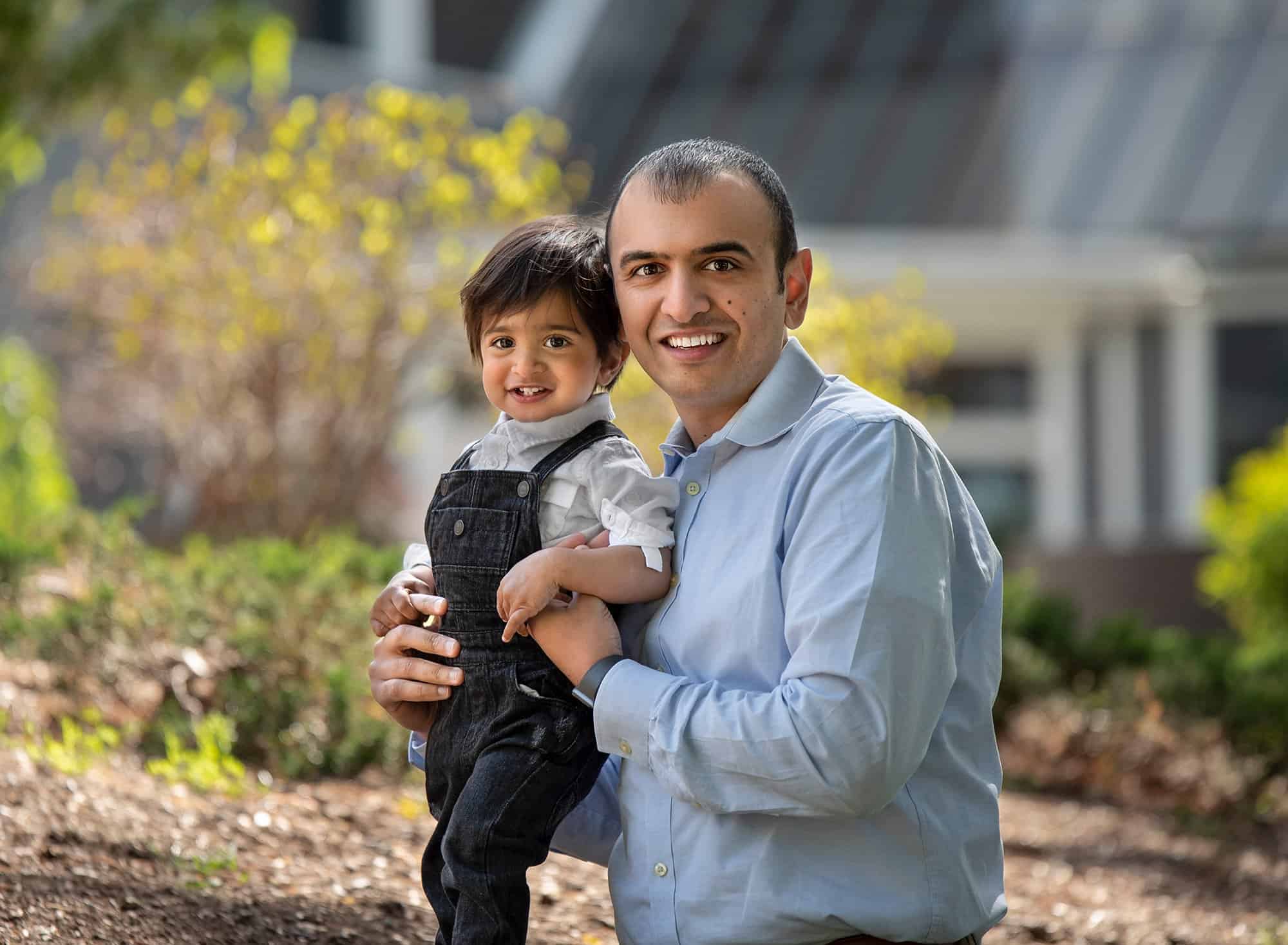 First Birthday Session dad smiling while holding his little boy dressed in overalls