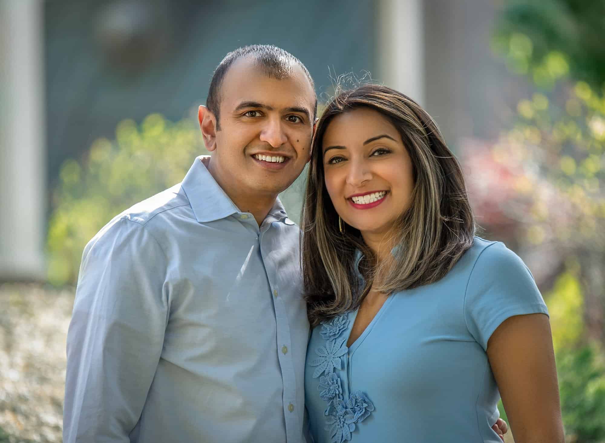 husband and wife standing next to each other outside dressed in blue