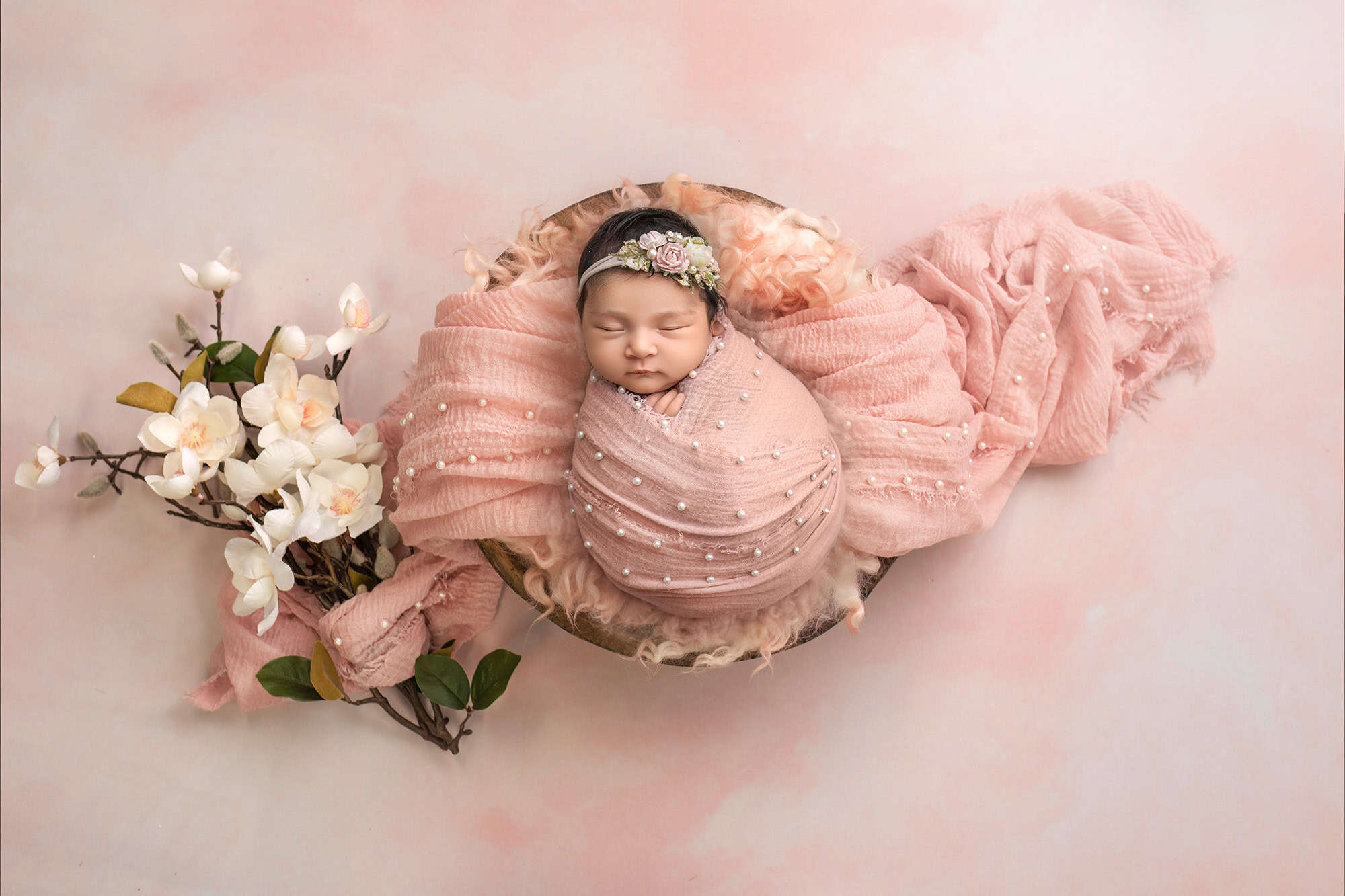 sleepy newborn portrait wrapped in blush with floral headband