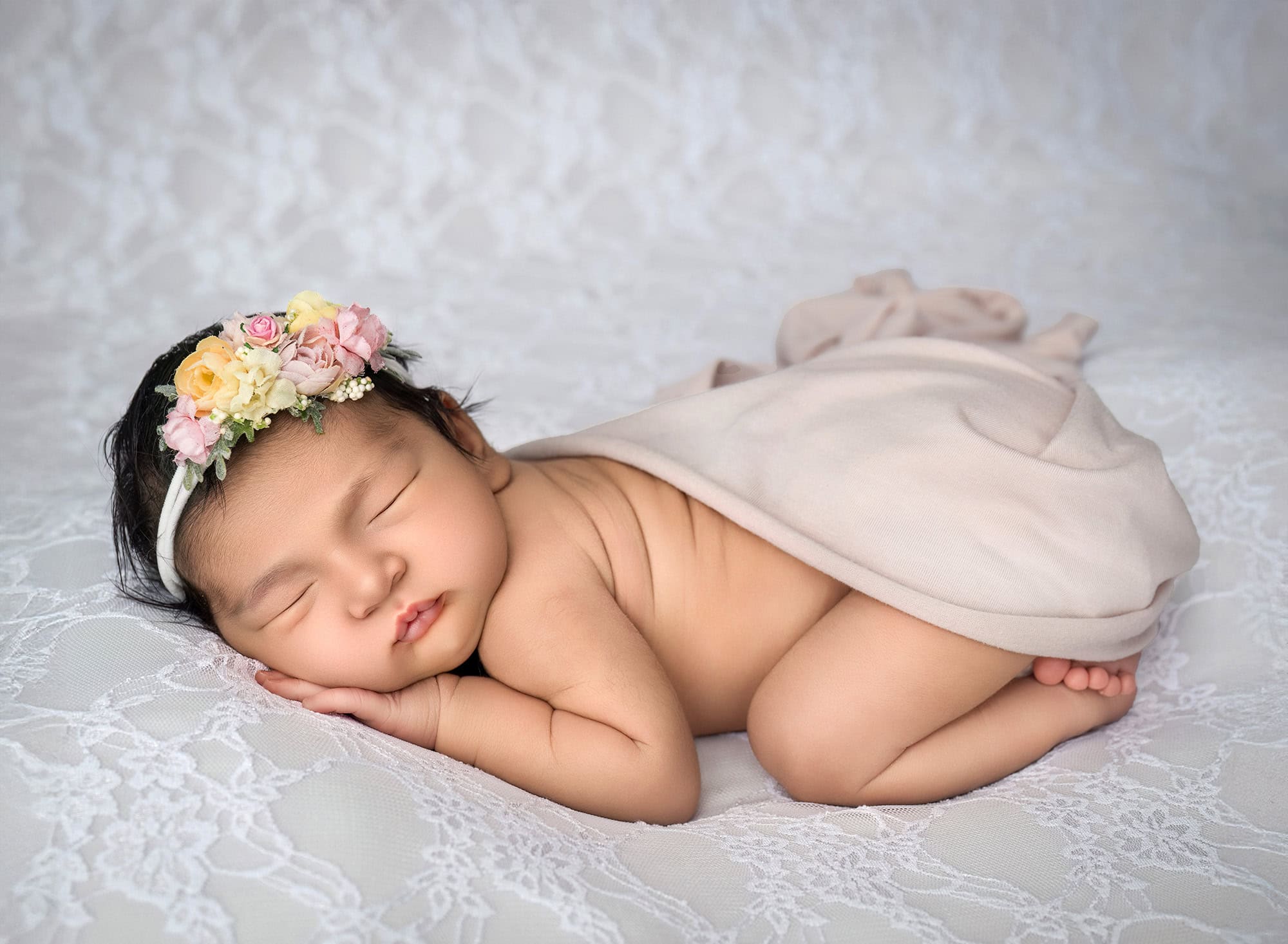 newborn photo of Elliana sleeping peacefully on her tummy on a white lace blanket