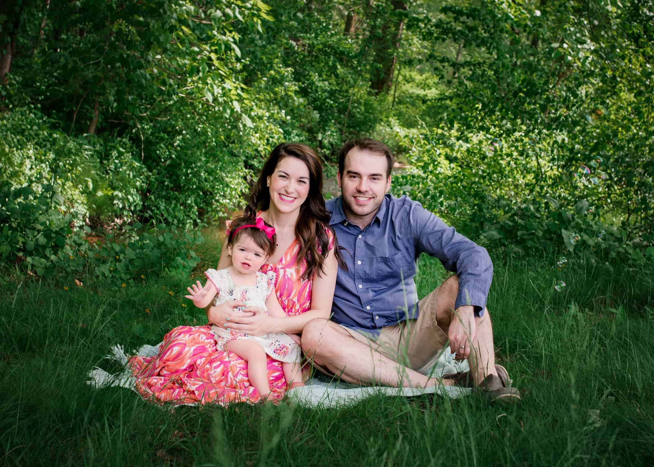 family photo of mom dad and baby girl in the garden in spring