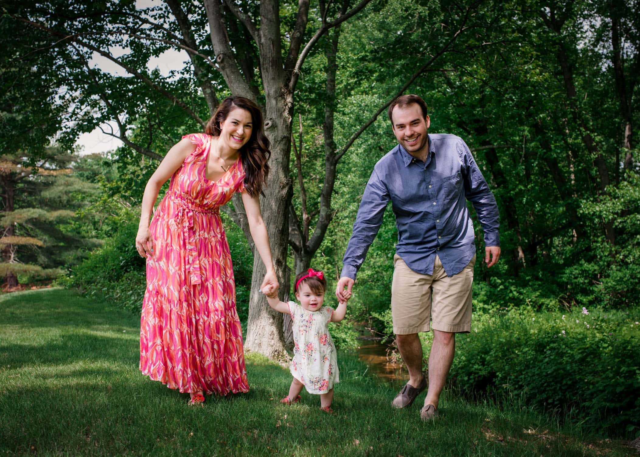 parents walking 1 year old baby girl in the garden
