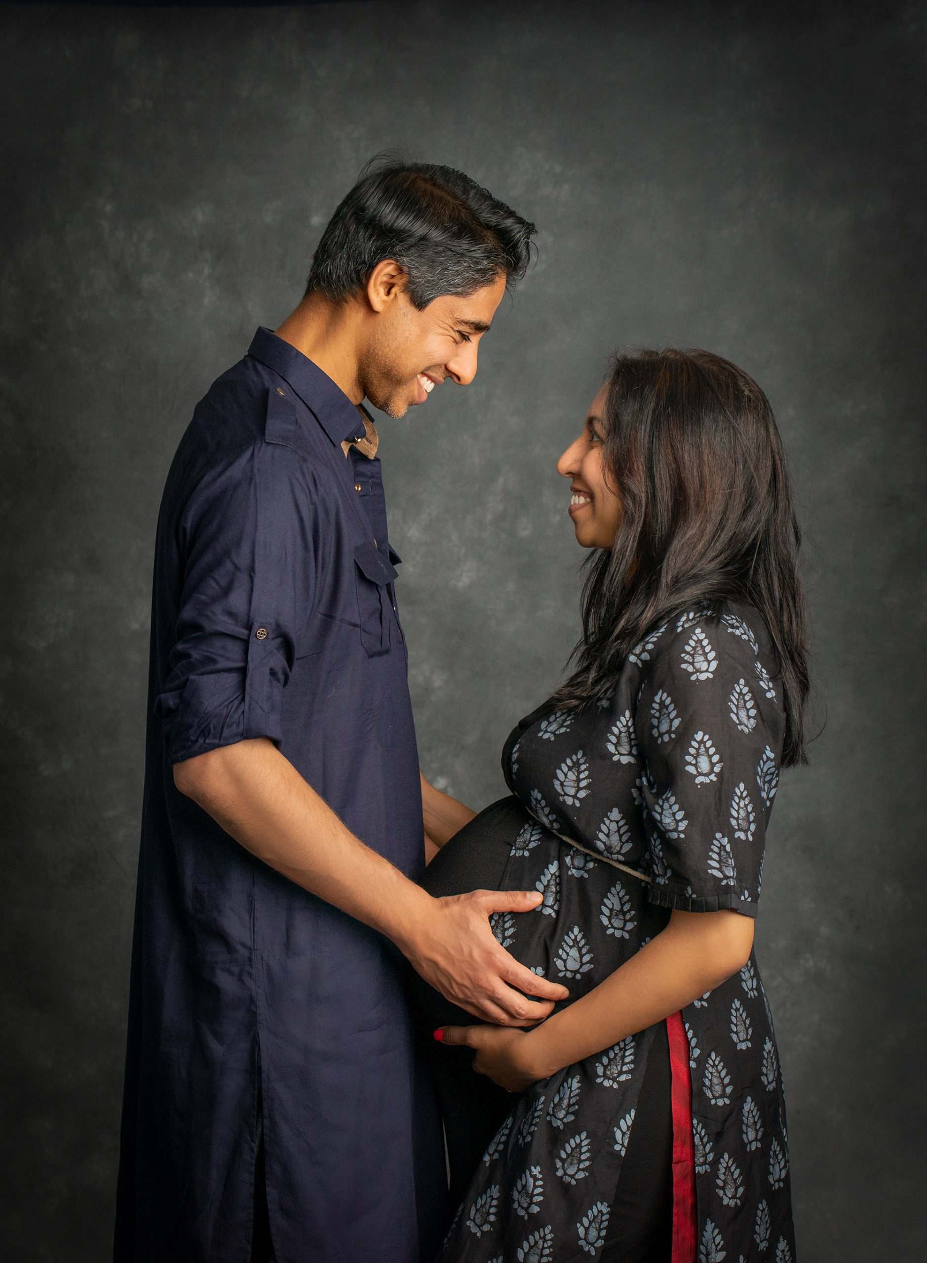 husband smiling while looking at pregnant wife