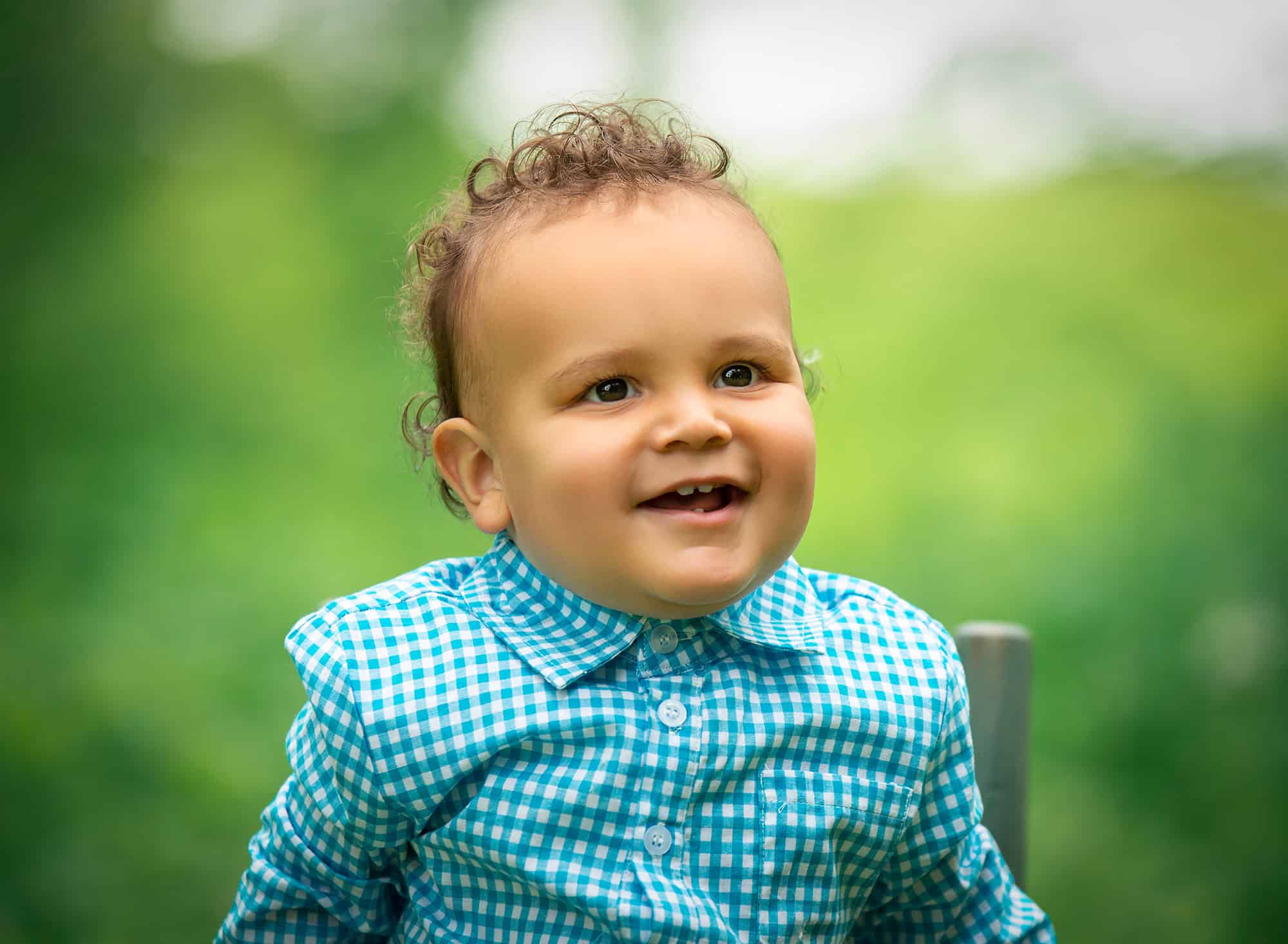 one year old curly haired boy smiling