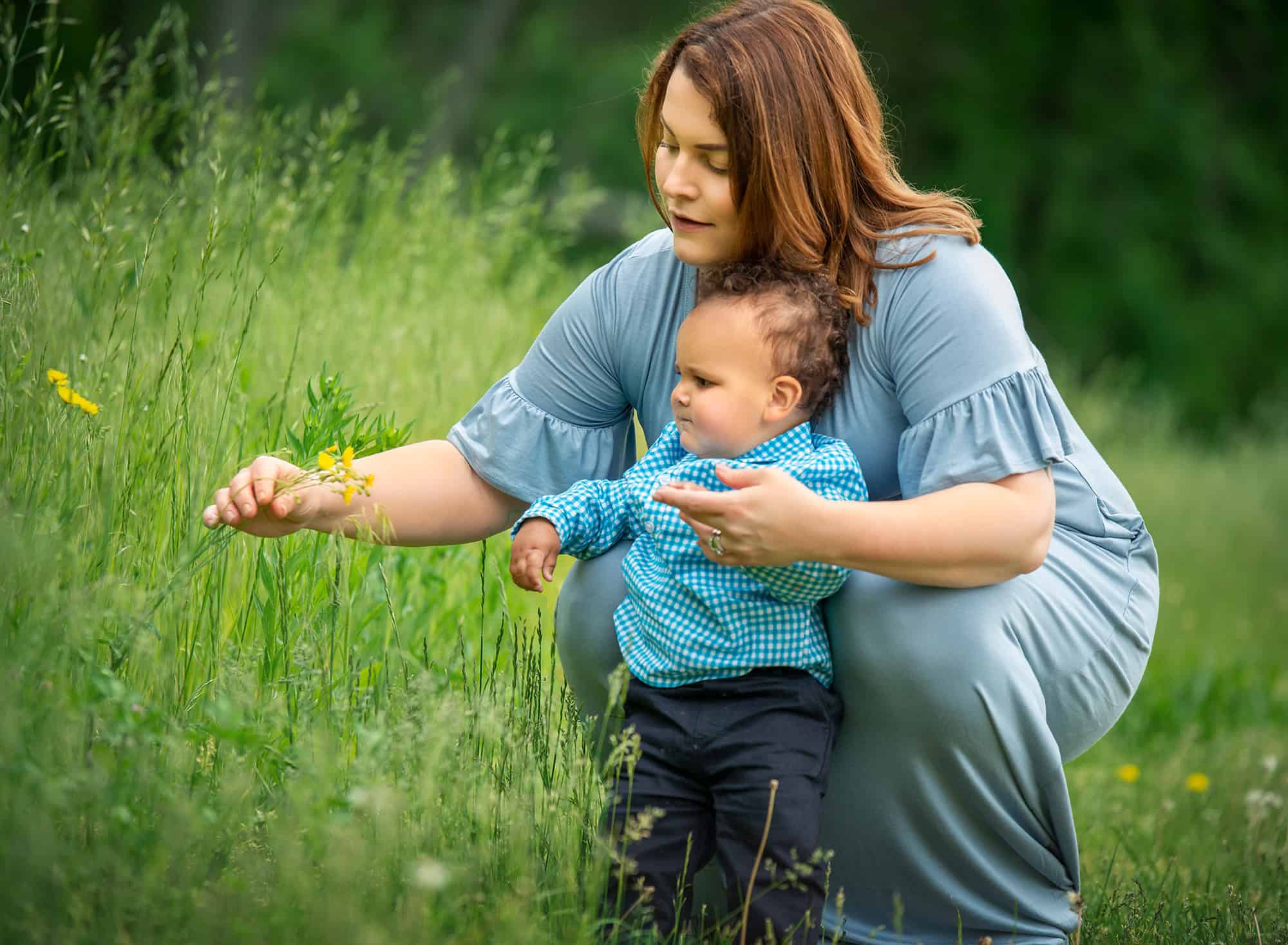 Family Photographers in CT mom picking flowers in a field with one year old baby boy