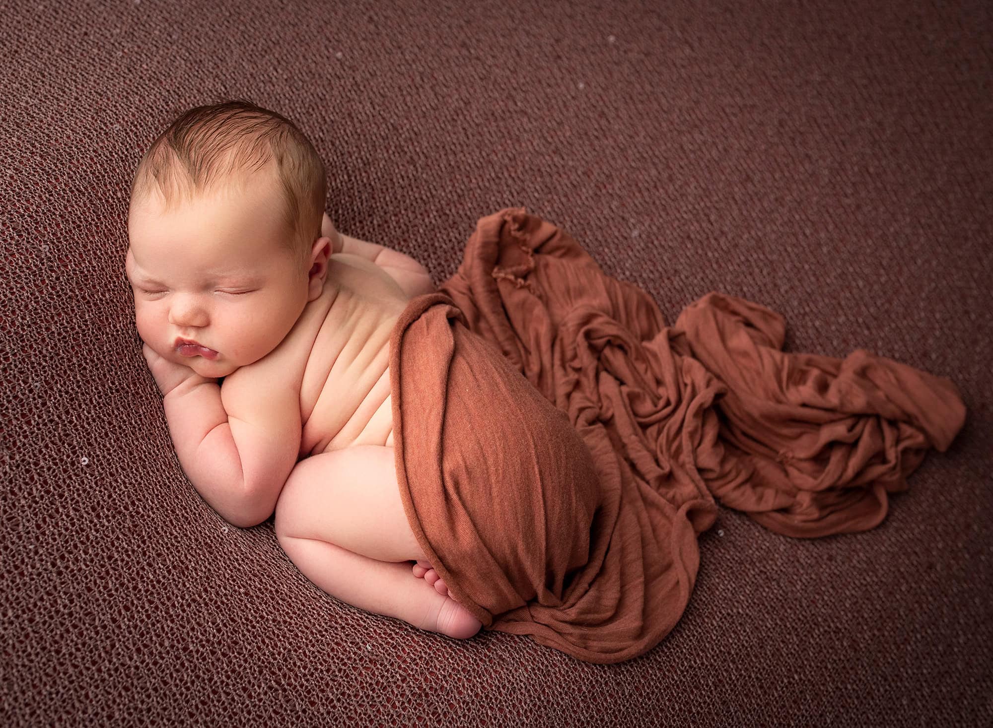 High school sweethearts newborn photos naked newborn baby boy asleep draped in orange
