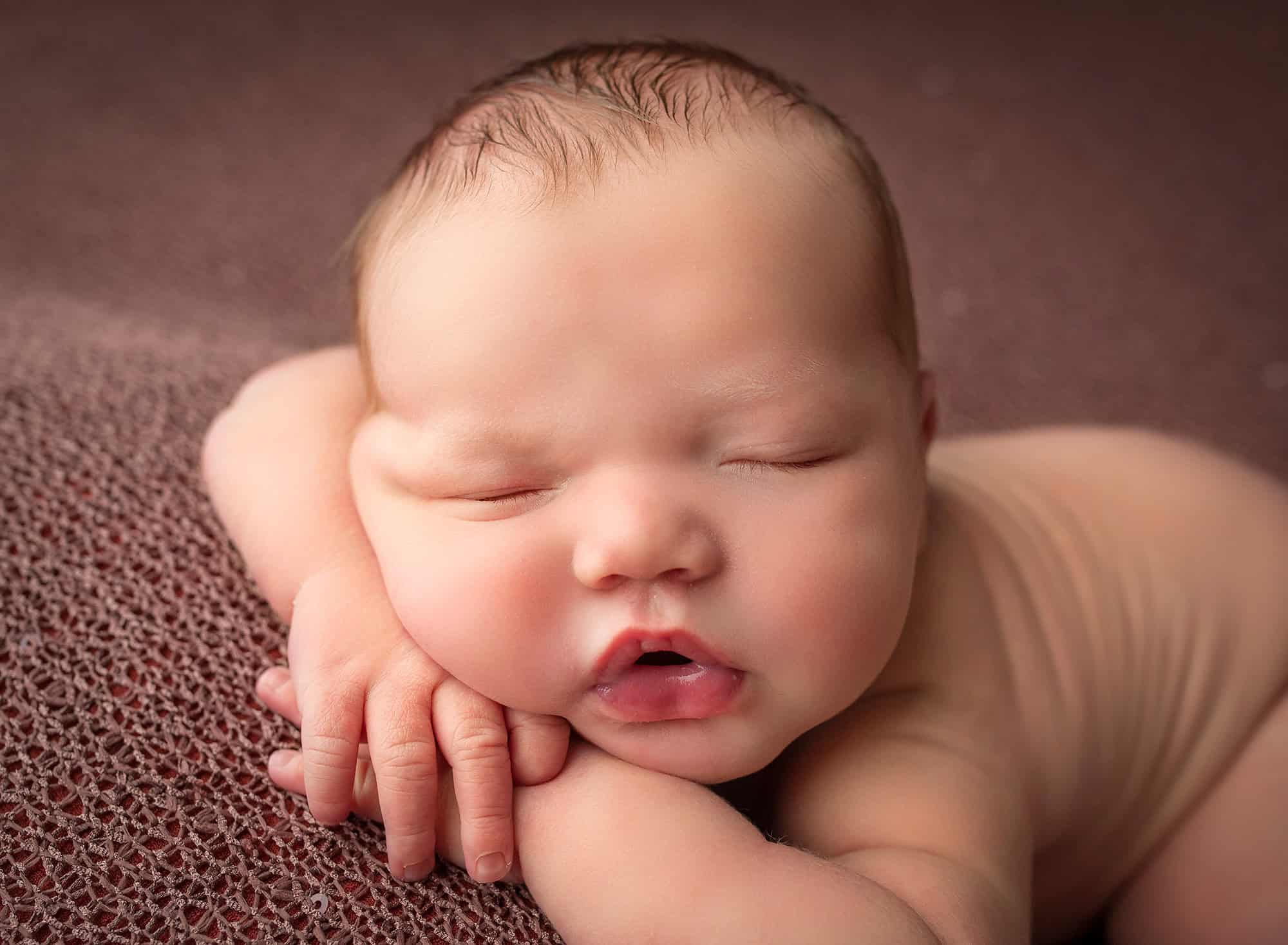 High school sweethearts newborn photos asleep naked newborn baby boy laying with his hands tucked underneath him