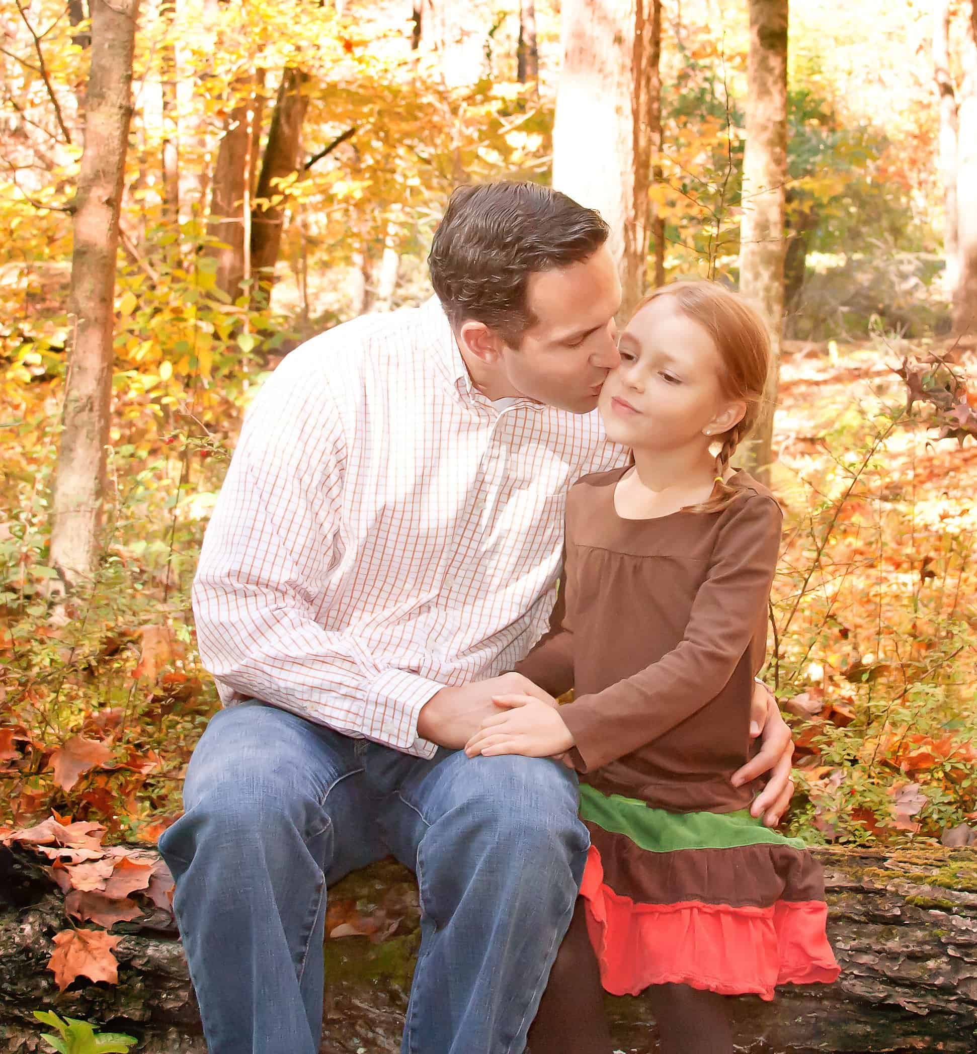 Dad and 6 year old daughter in the woods sitting