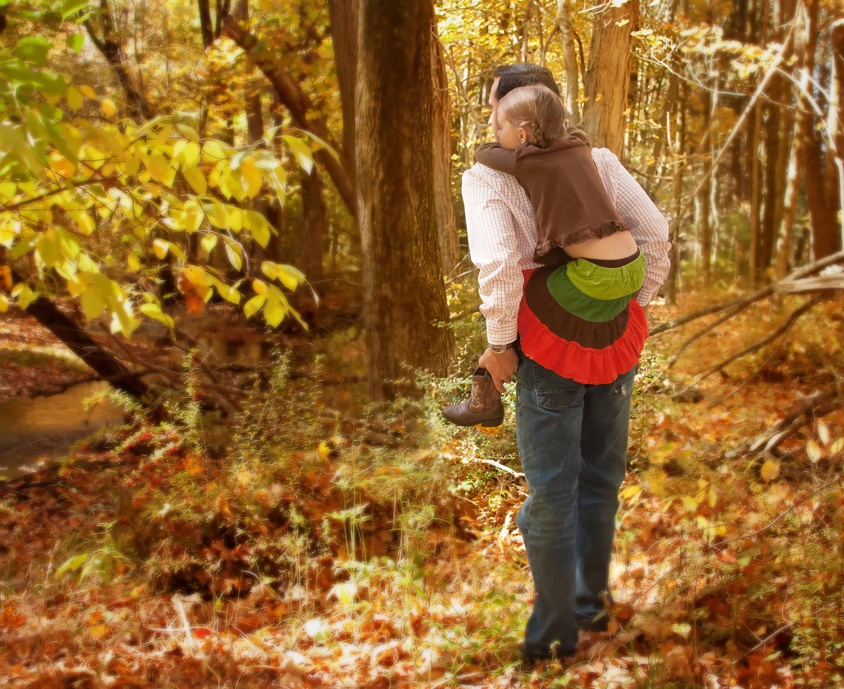 Dad giving piggy back ride to young daughter in the woods